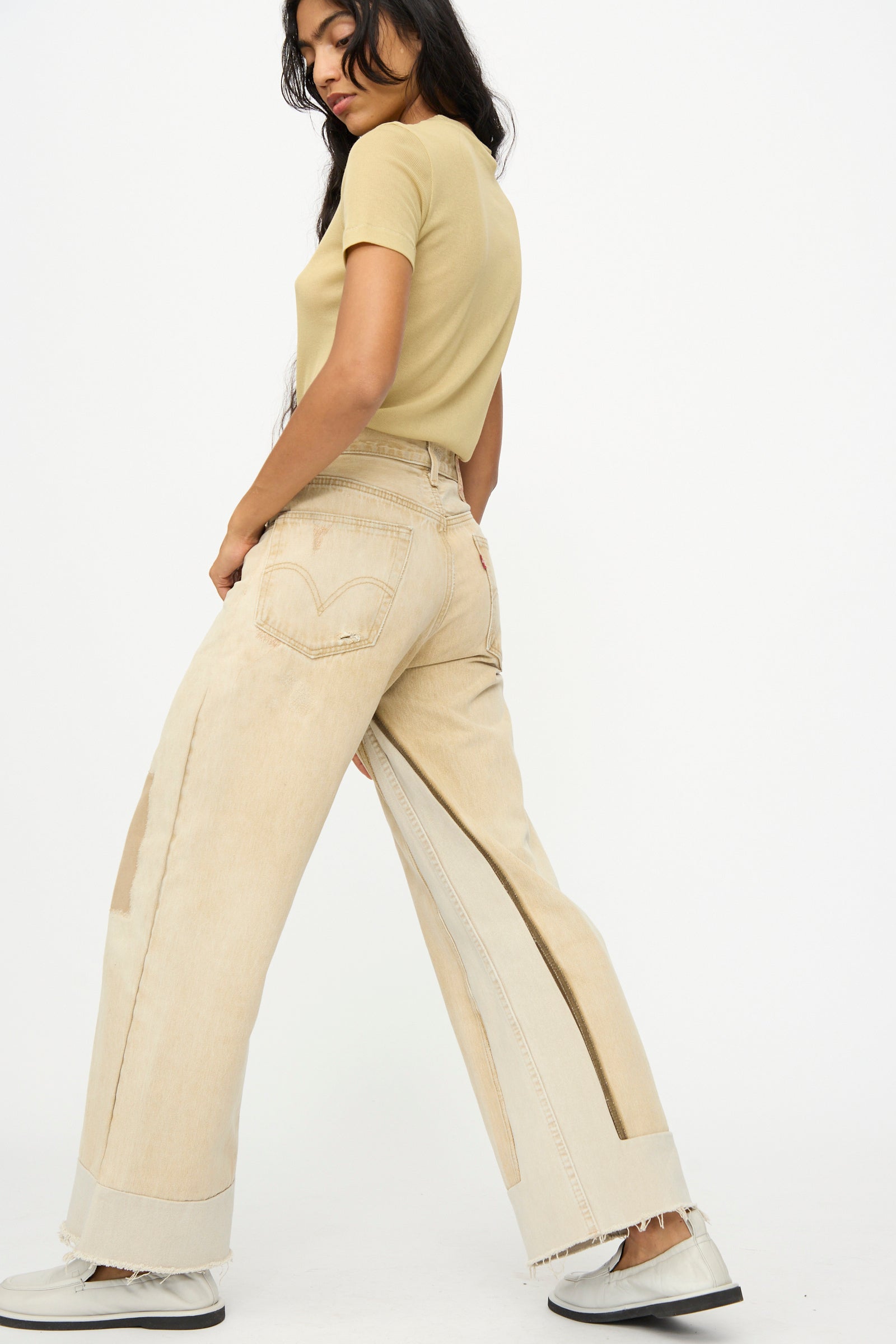 A woman wears the B Sides Reworked Vintage Culotte in Khaki and a beige t-shirt, paired with white shoes, as she stands against a plain white background.