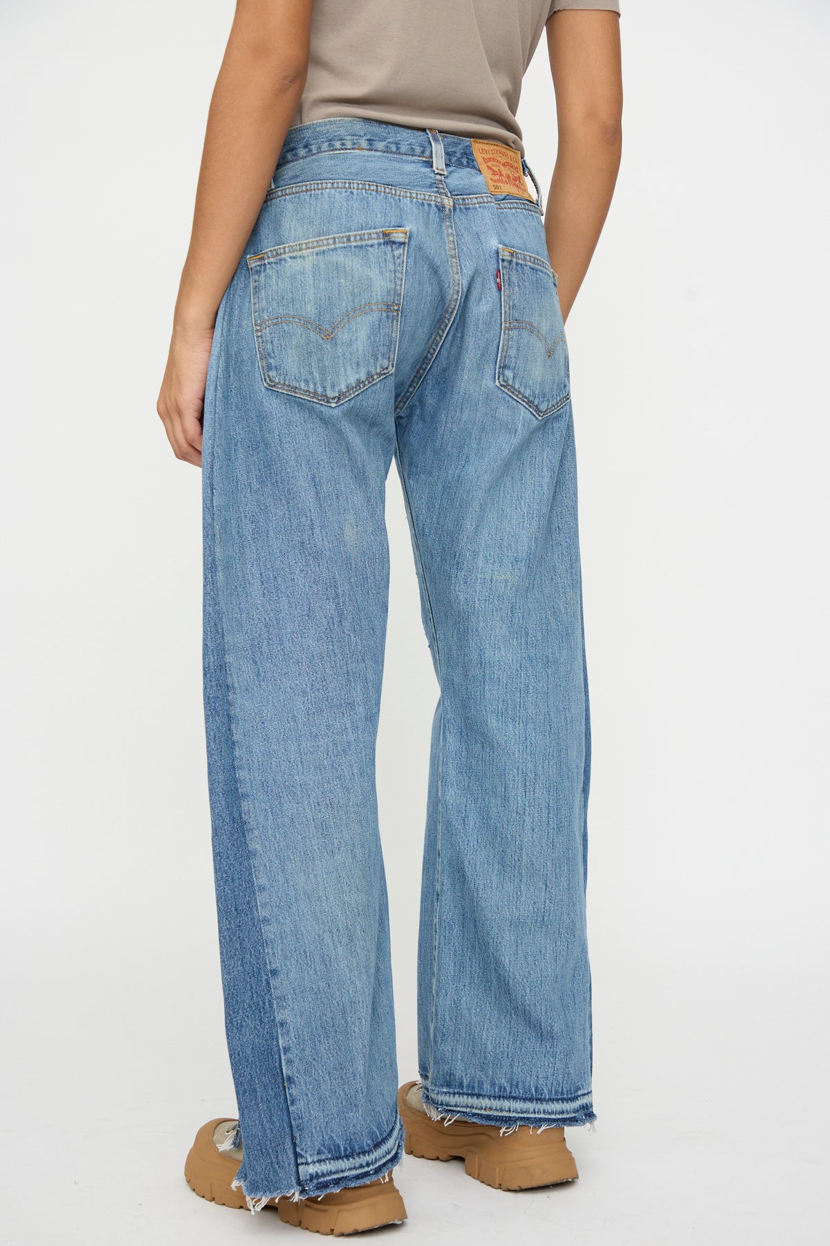 Model wears B Sides Reworked Vintage Open Hem Slouch in Indigo and tan shoes, shown from the back against a plain white background.