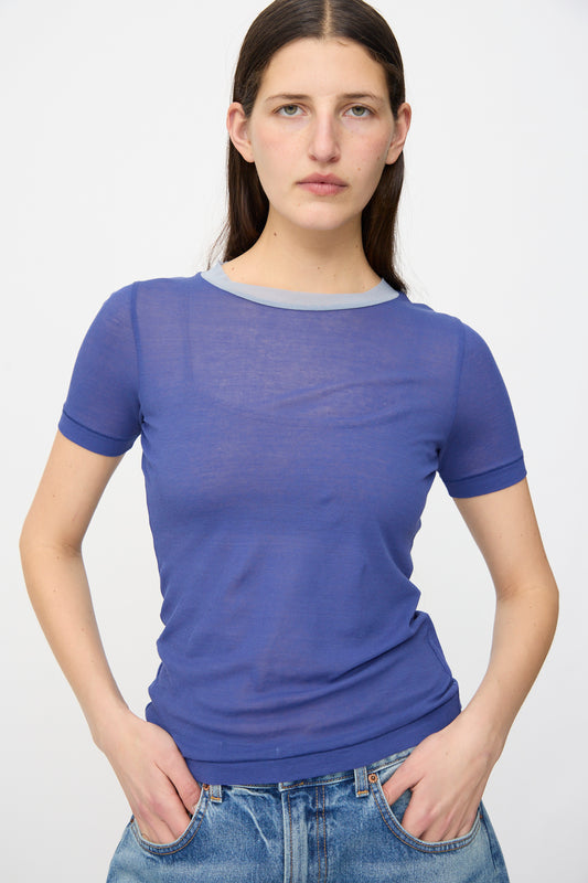 A person stands facing the camera with hands in pockets, wearing the B Sides Ringer Tee in Bright Blue and blue jeans against a plain background.