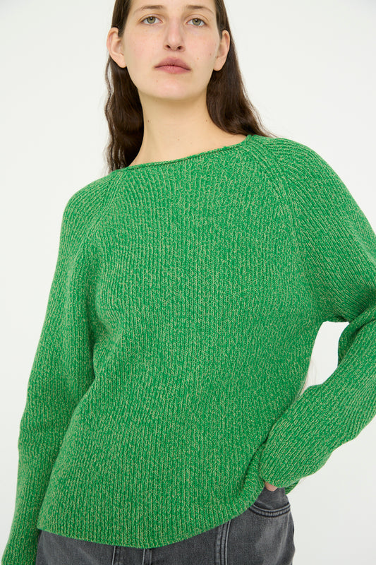 A model stands against a plain white background wearing the B Sides Shaker Stitch Roll Neck in Green and Peach, paired with jeans.