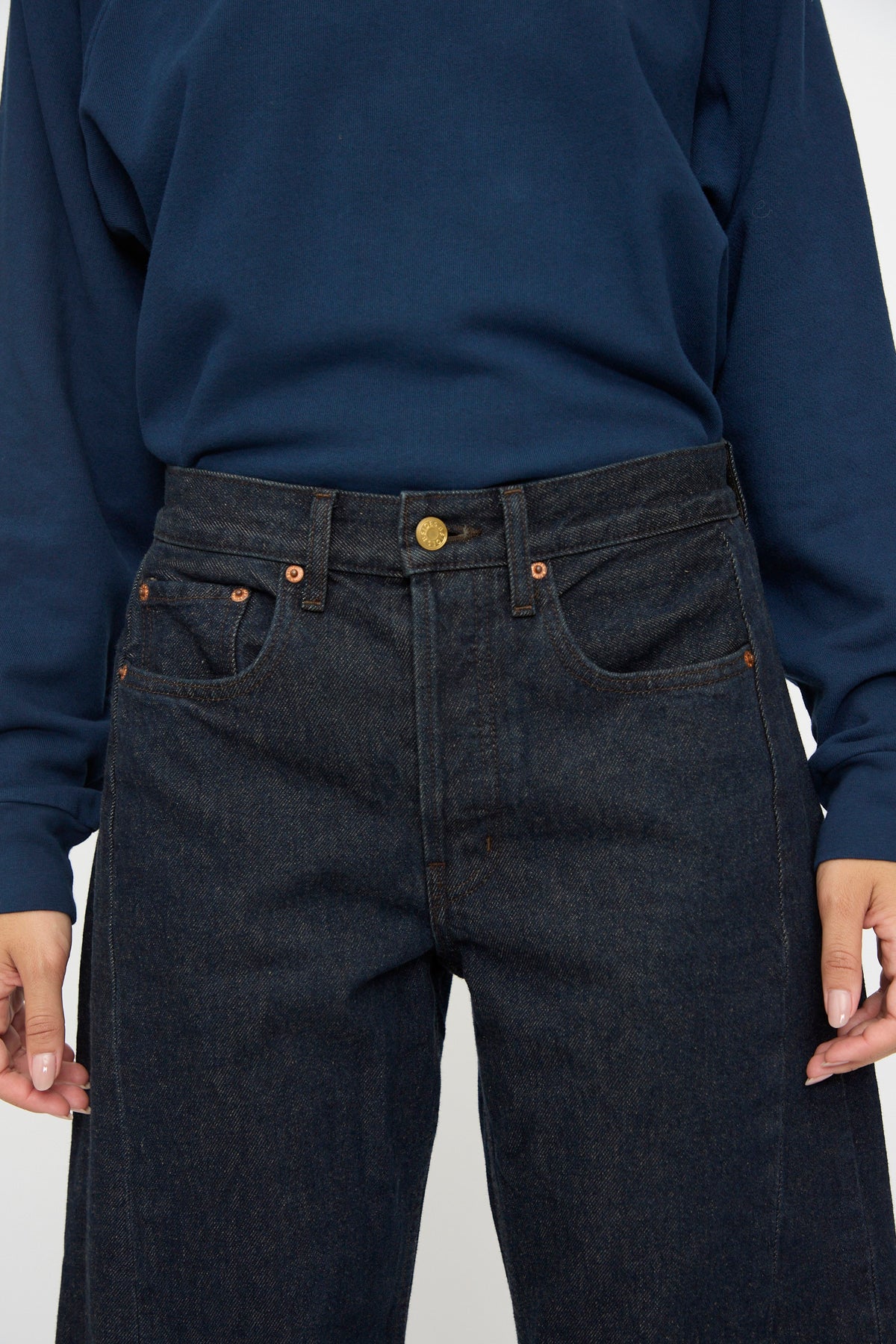 Model wears B Sides Slim Lasso in Indigo Brown Rinse, shown from shoulders to mid-thigh with a dark blue long-sleeve shirt.