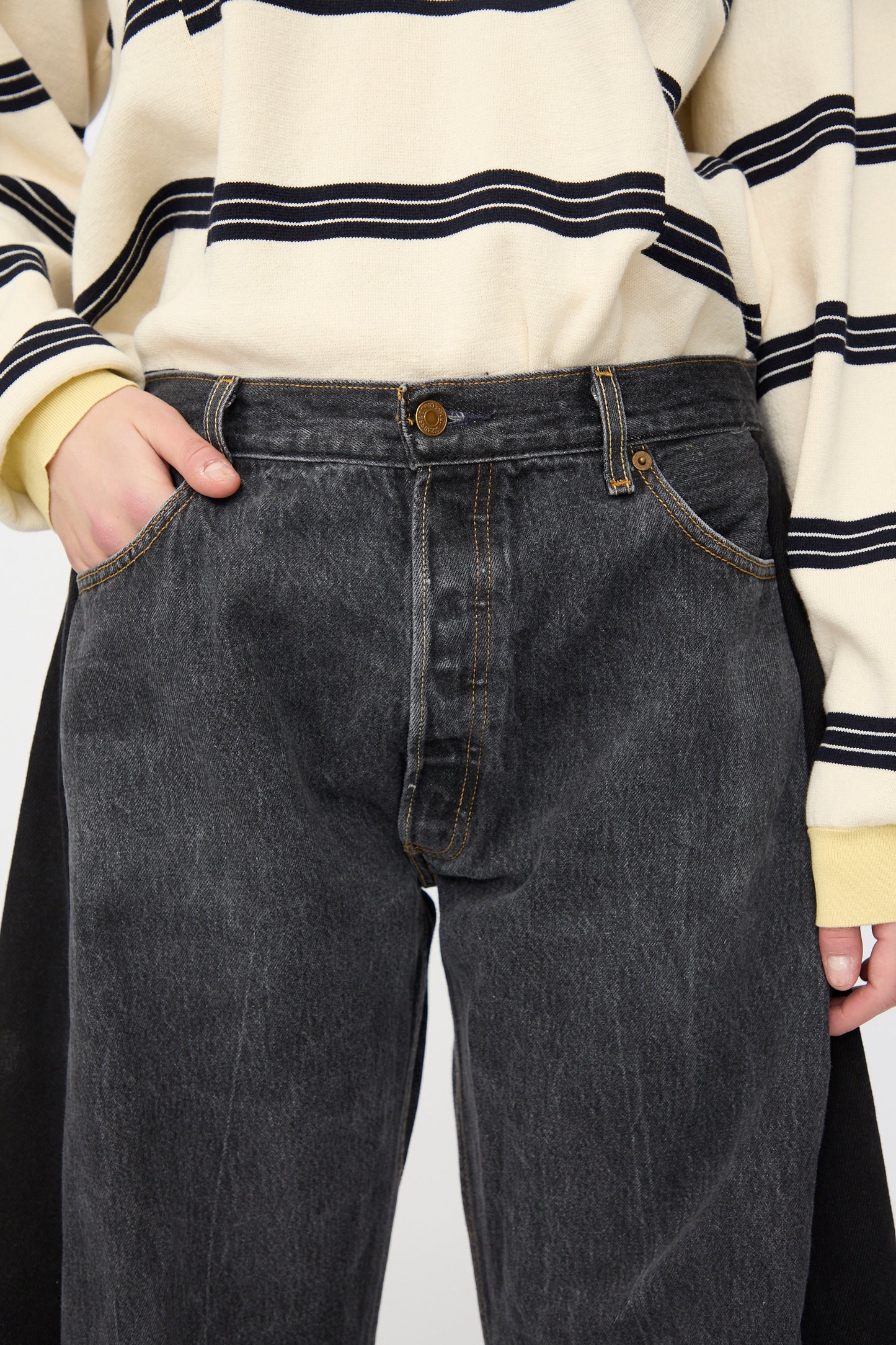 Person wearing a cream and black striped long-sleeve shirt and B Sides Vintage Lasso Jean in Black, with one hand in a pocket.