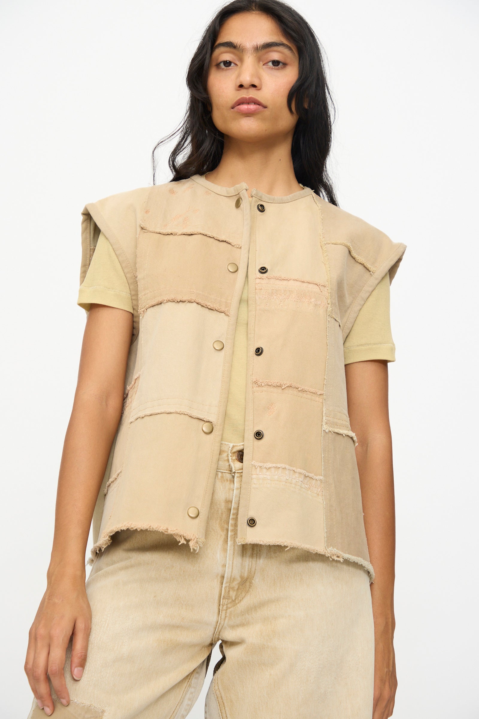 A person wears the B Sides Vintage Madras Vest in Khaki over a light yellow t-shirt and beige pants, standing against a plain white background.