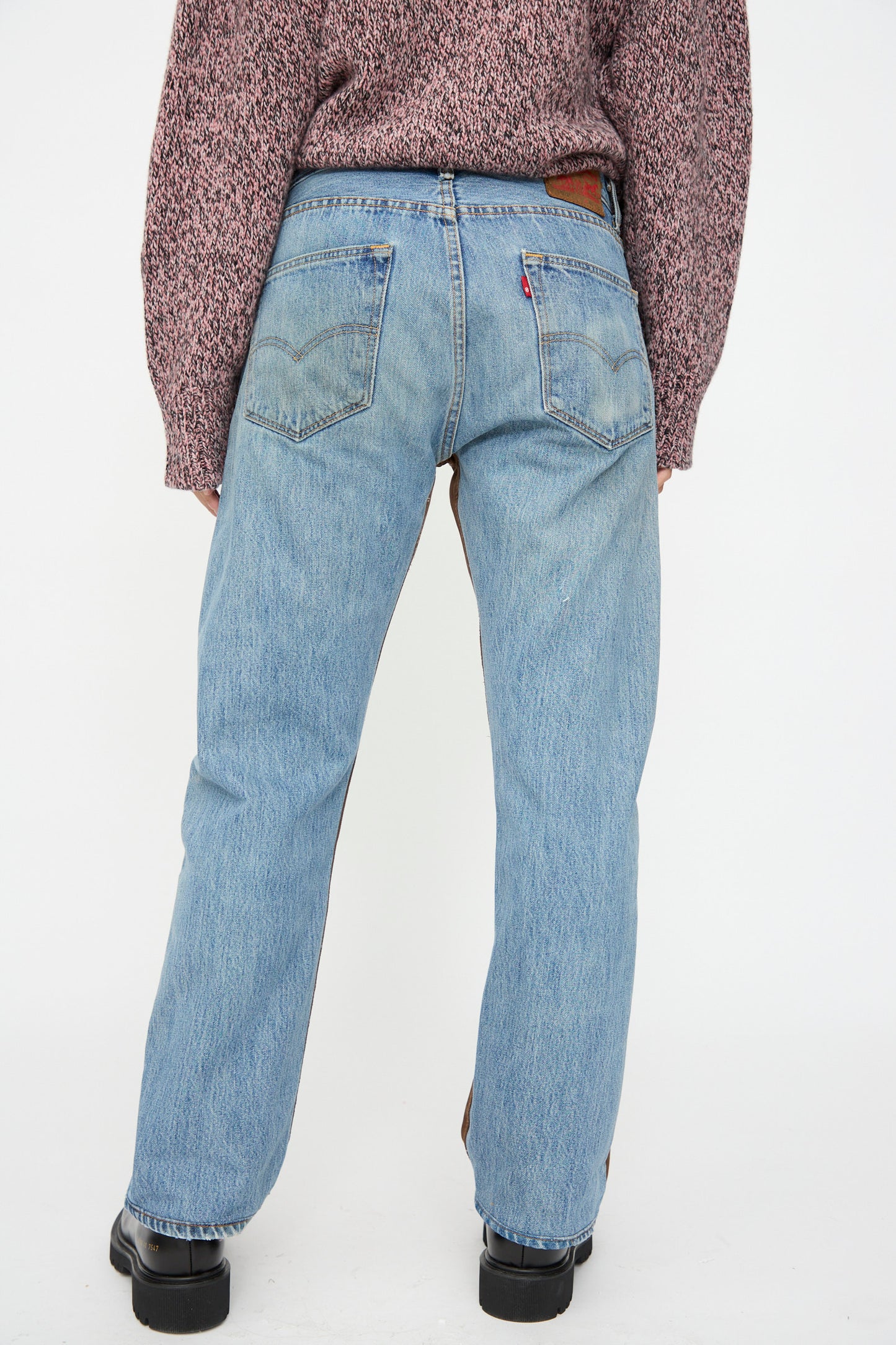 Person wearing B Sides Vintage Straight Rework Halfsie jeans in brown and indigo, styled with a textured maroon sweater and black shoes, standing with their back to the camera against a plain white background.