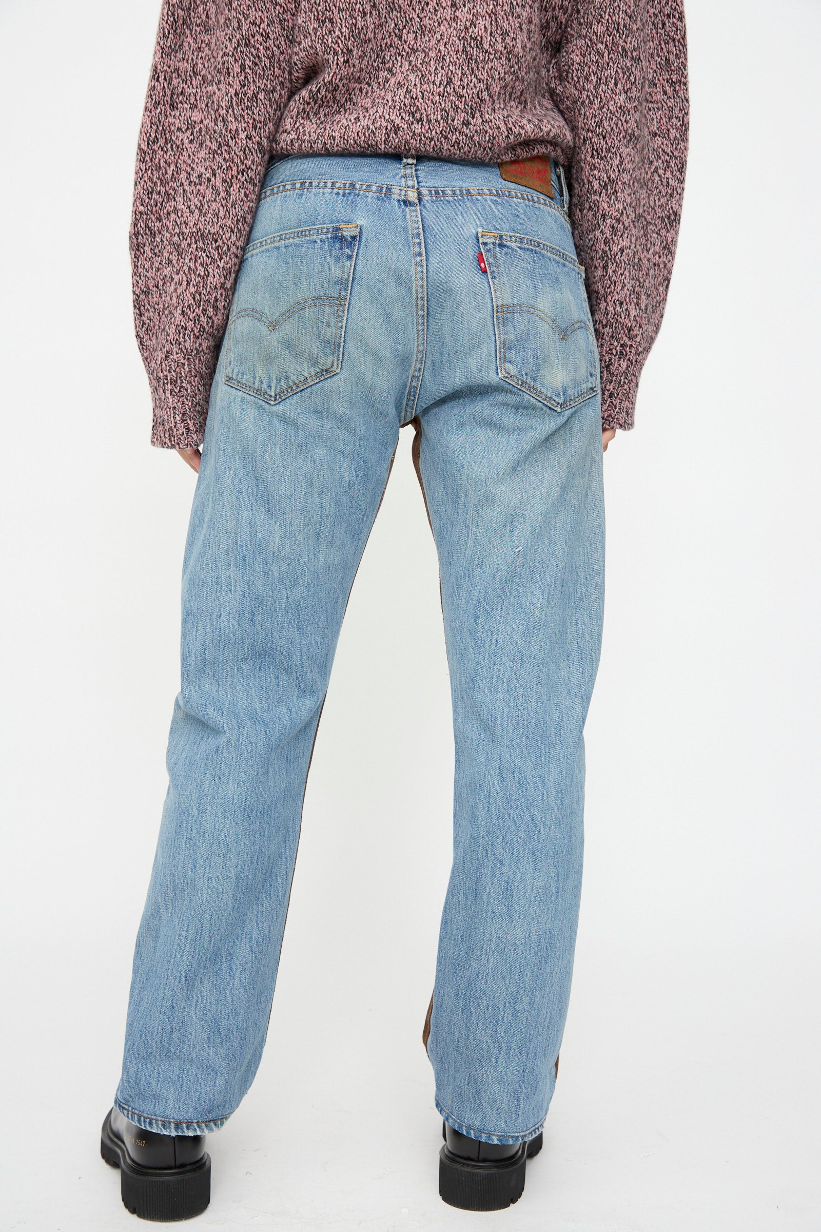 Person wearing B Sides Vintage Straight Rework Halfsie jeans in brown and indigo, styled with a textured maroon sweater and black shoes, standing with their back to the camera against a plain white background.