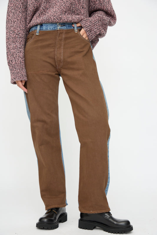 A person stands against a plain background wearing B Sides' Vintage Straight Rework Halfsie in Brown and Indigo, styled with a patterned sweater and black boots.
