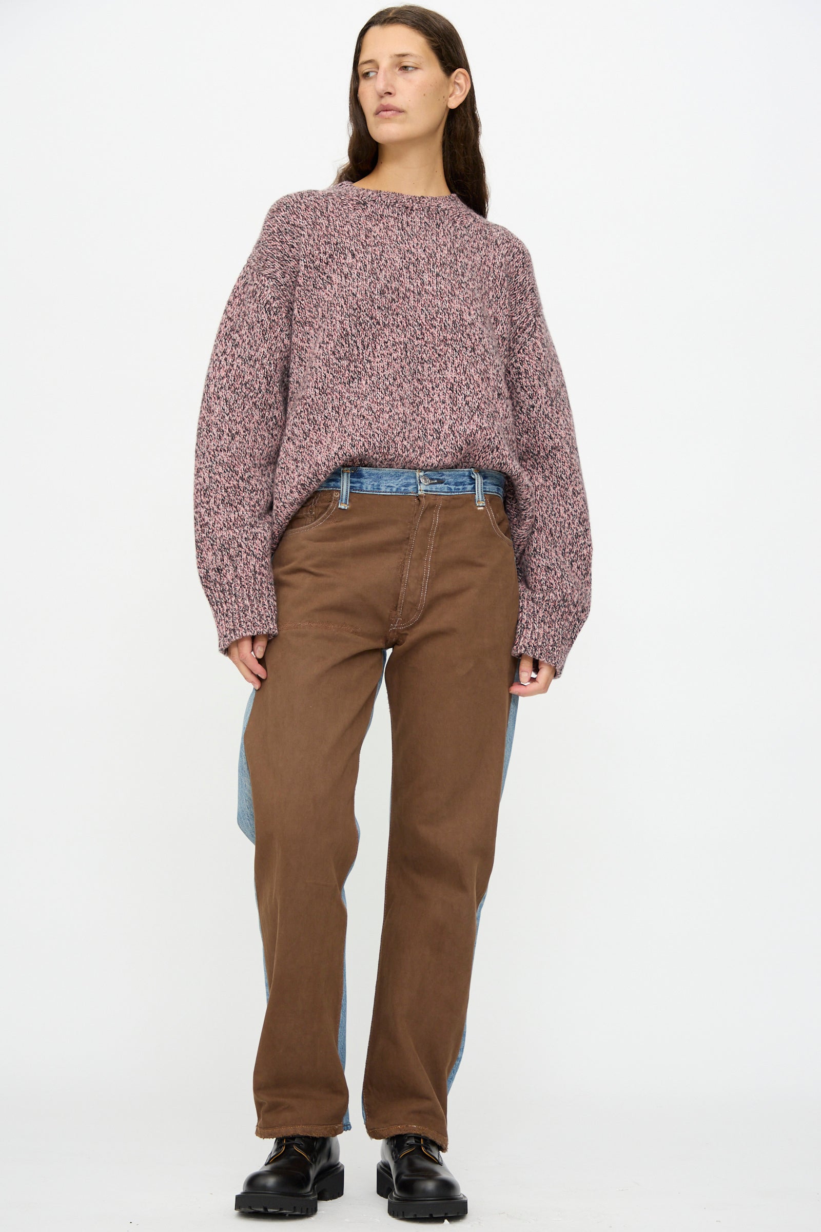 A person stands against a white background wearing a maroon knit sweater, black shoes, and the B Sides Vintage Straight Rework Halfsie in Brown and Indigo—brown pants featuring reworked 100% cotton denim blue panels.