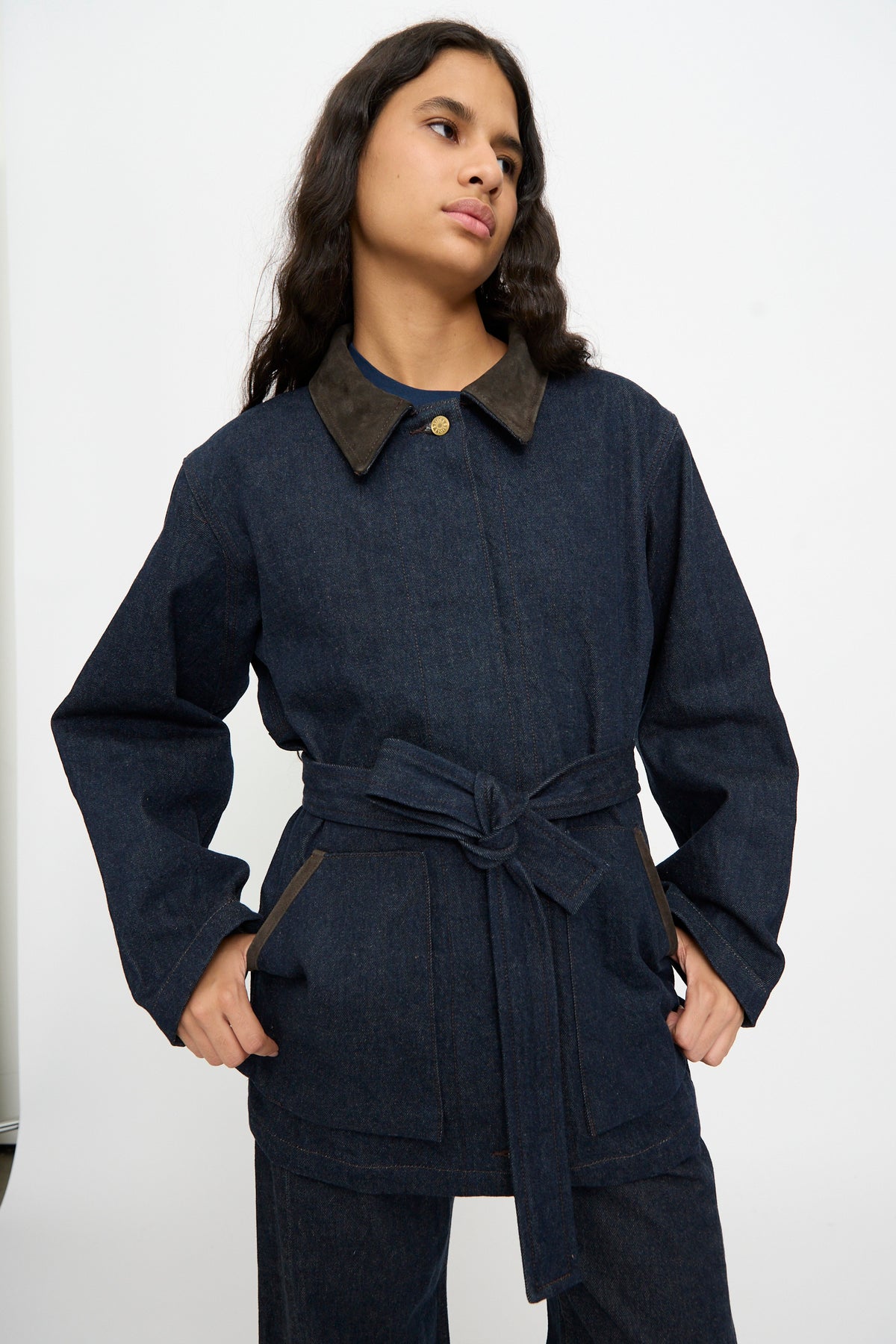Model poses with hands on hips in the B Sides Workwear Jacket in Indigo Rinse and Espresso Suede against a plain white background.