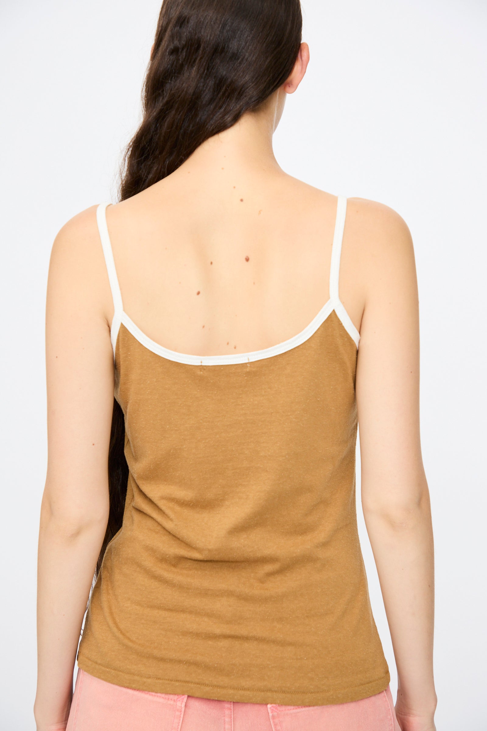 A person with long dark hair is shown from the back wearing the B Sides Zora Ringer Tank in Camel and White, paired with pink bottoms, against a plain background.