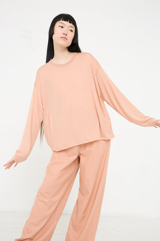 A woman in a Yu Rose Bamboo Loose Long Sleeve Tee by Baserange, posing against a white background.