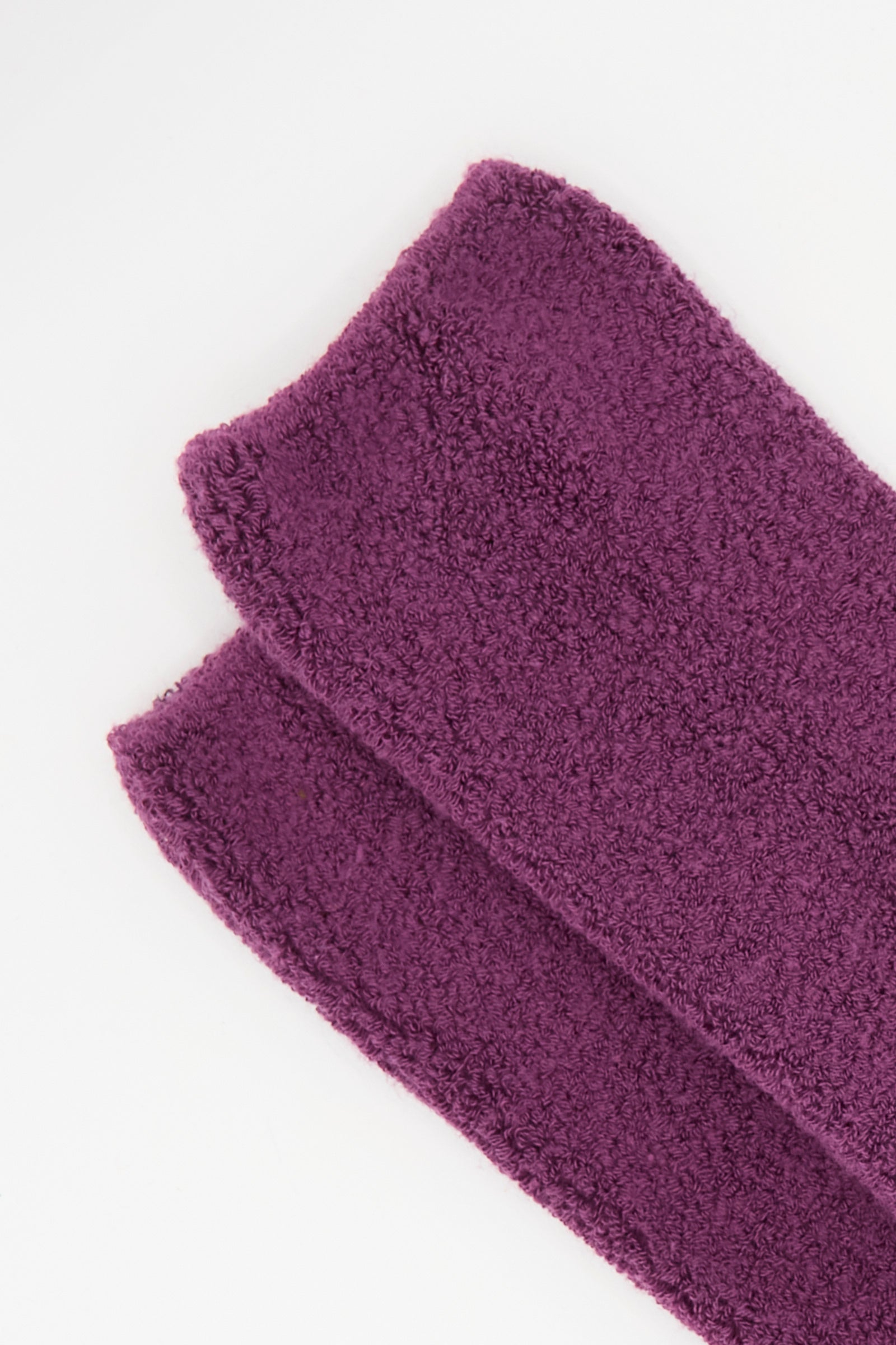 A folded, rectangular purple terry cloth towel sits on a white background, complementing the Baserange Buckle Overankle Socks in Gesso Purple.