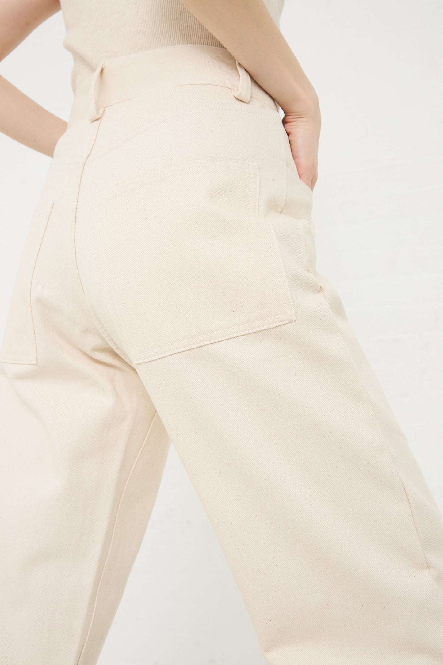 Close-up of a model wearing Baserange brand Organic Cotton Indre Pant in Undyed, emphasizing the back pocket and waistband detailing.