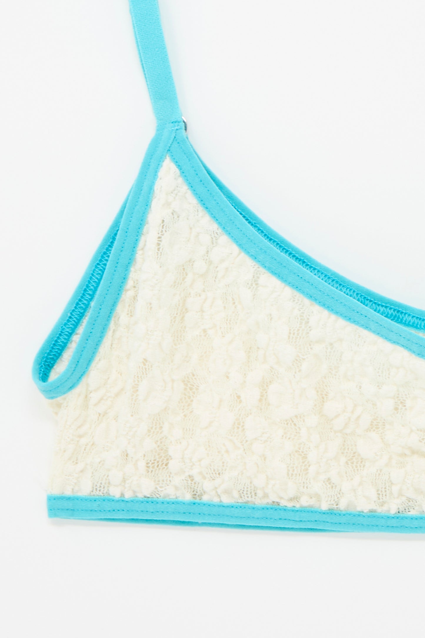 Close-up of the Cotton Lace Musial Bra by Baserange, showcasing an undyed lace cup with turquoise trim and straps.