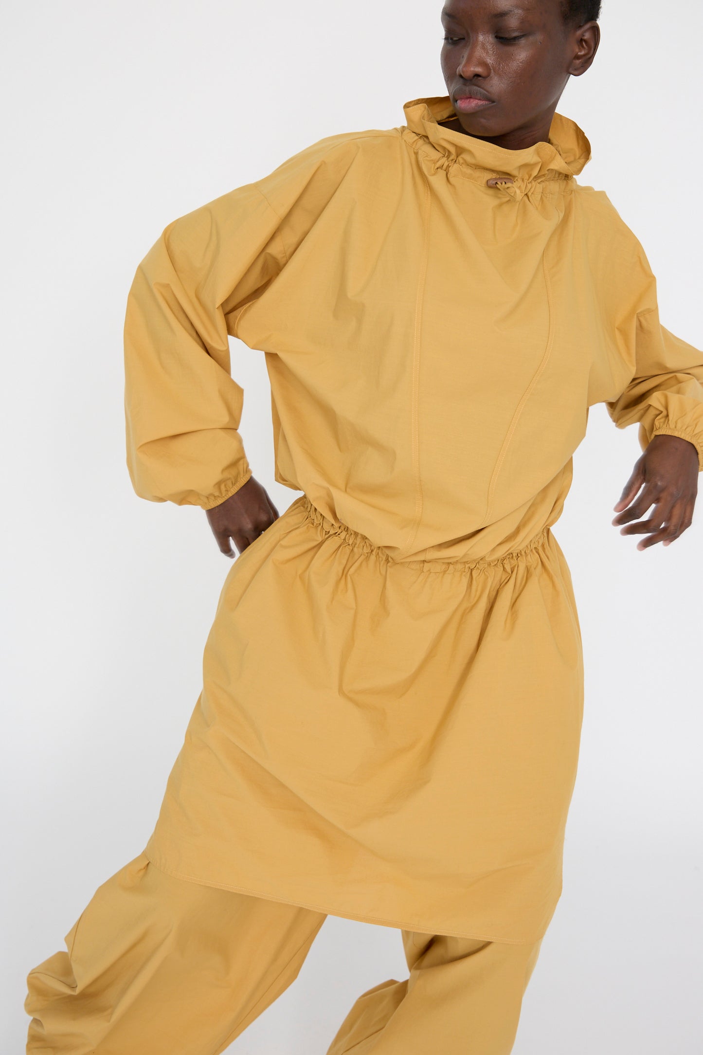 A person poses against a plain white background, wearing the oversized Baserange Cotton Poplin Air Dress in Sighs Yellow, crafted from plush organic cotton.