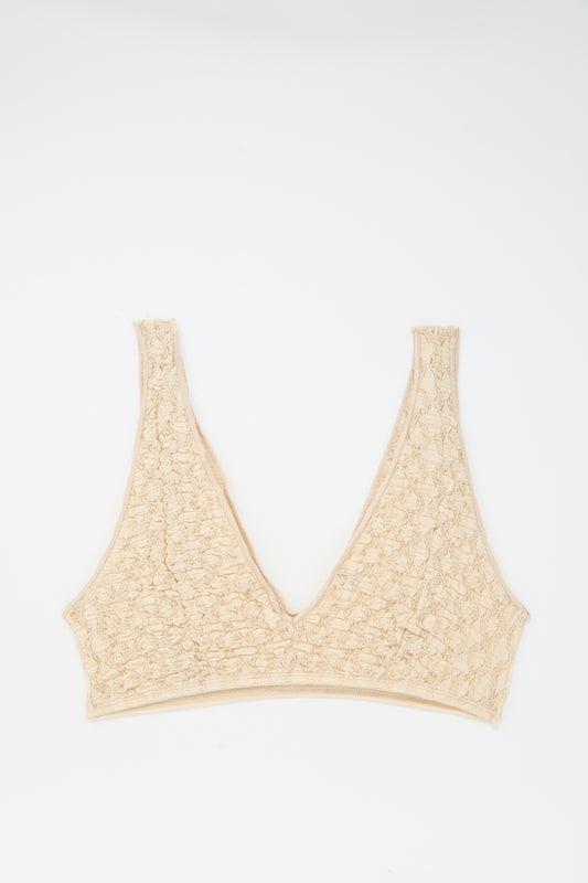 The Crescent Bra in Dylan Beige by Baserange features a textured V-neck, wide straps, and elastic trim, shown laid flat on a white background.