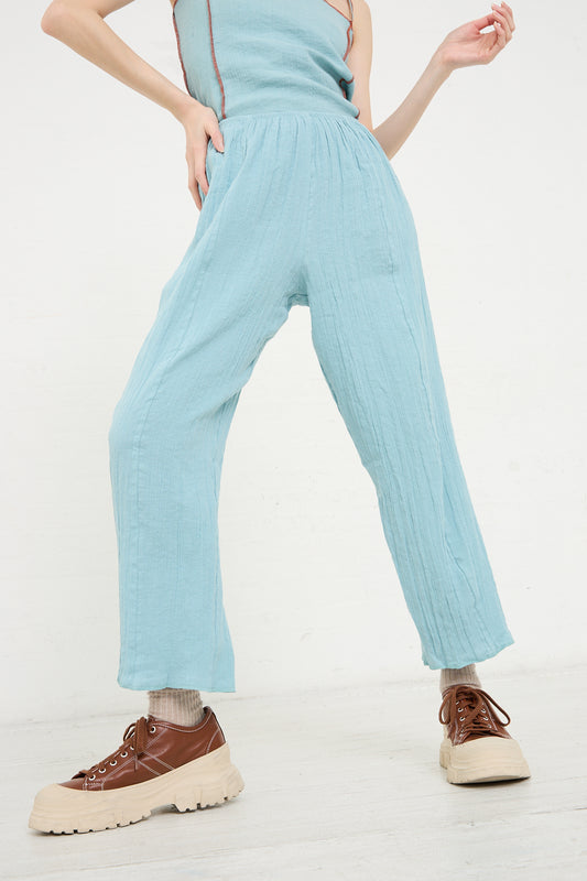 Woman in Crinkle Linen Cotton Shok Pant in Wuxi Blue by Baserange and chunky lace-up shoes walking against a white background.