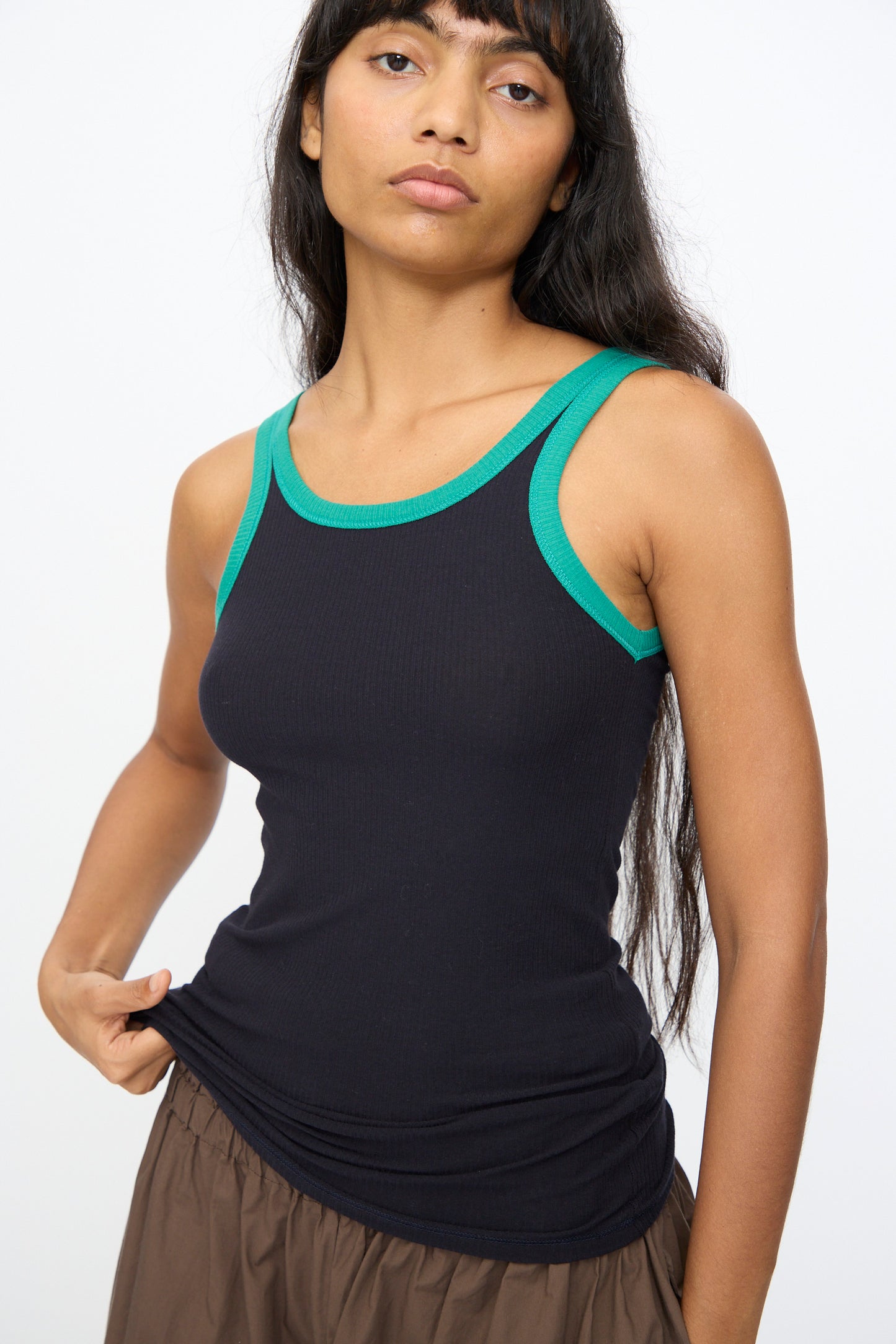 A person wearing the Baserange Drive Tank in Murano Navy and a brown skirt stands against a plain white background.