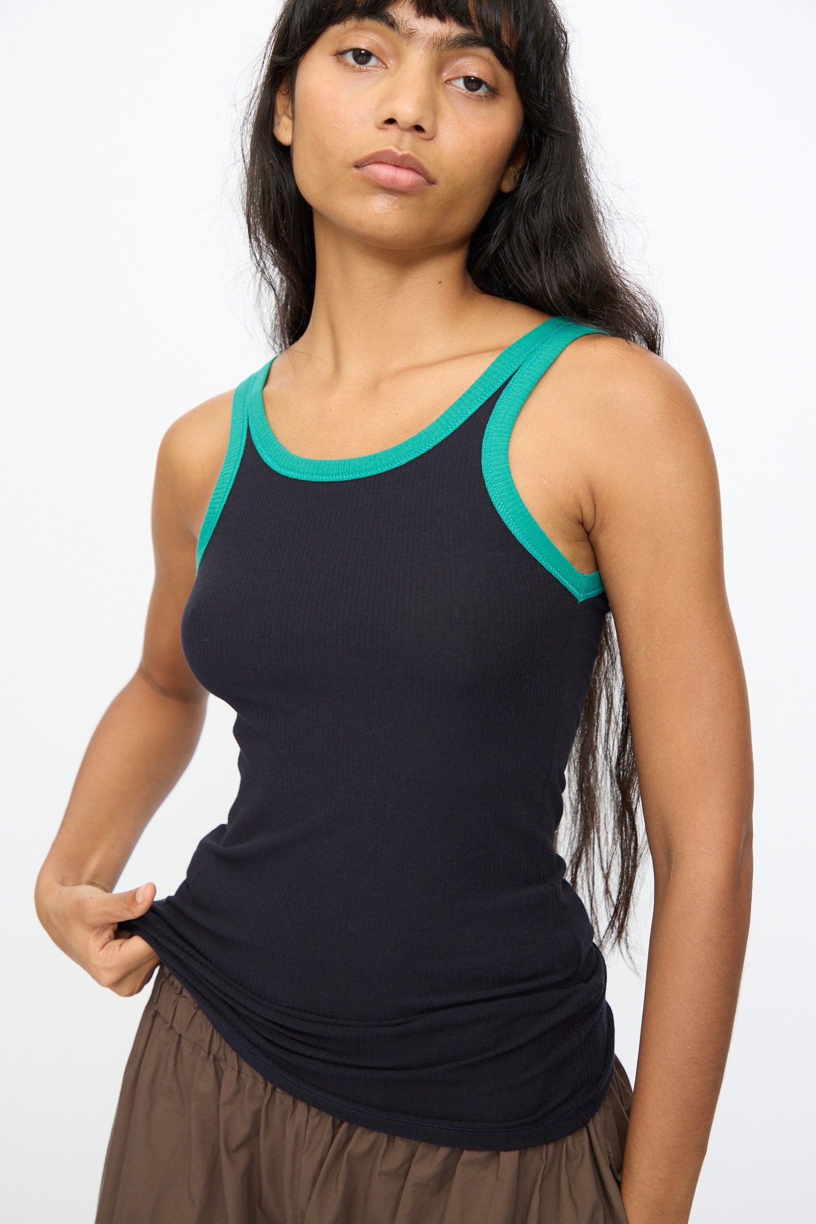 A person wearing the Baserange Drive Tank in Murano Navy and a brown skirt stands against a plain white background.