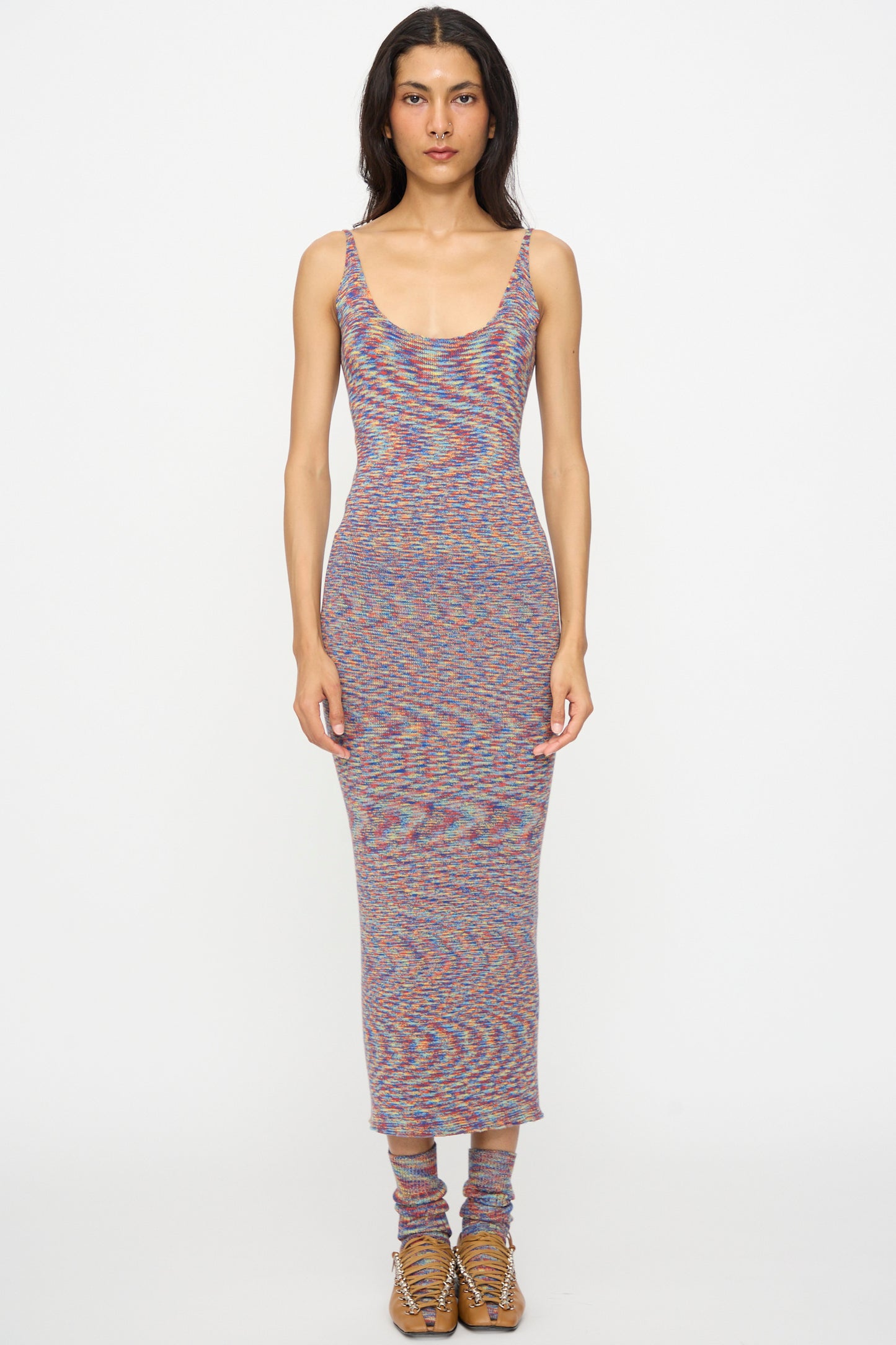 A person stands facing forward against a plain white background, wearing the Baserange Flute Dress in Multicolored, paired with matching knit socks and tan lace-up shoes.