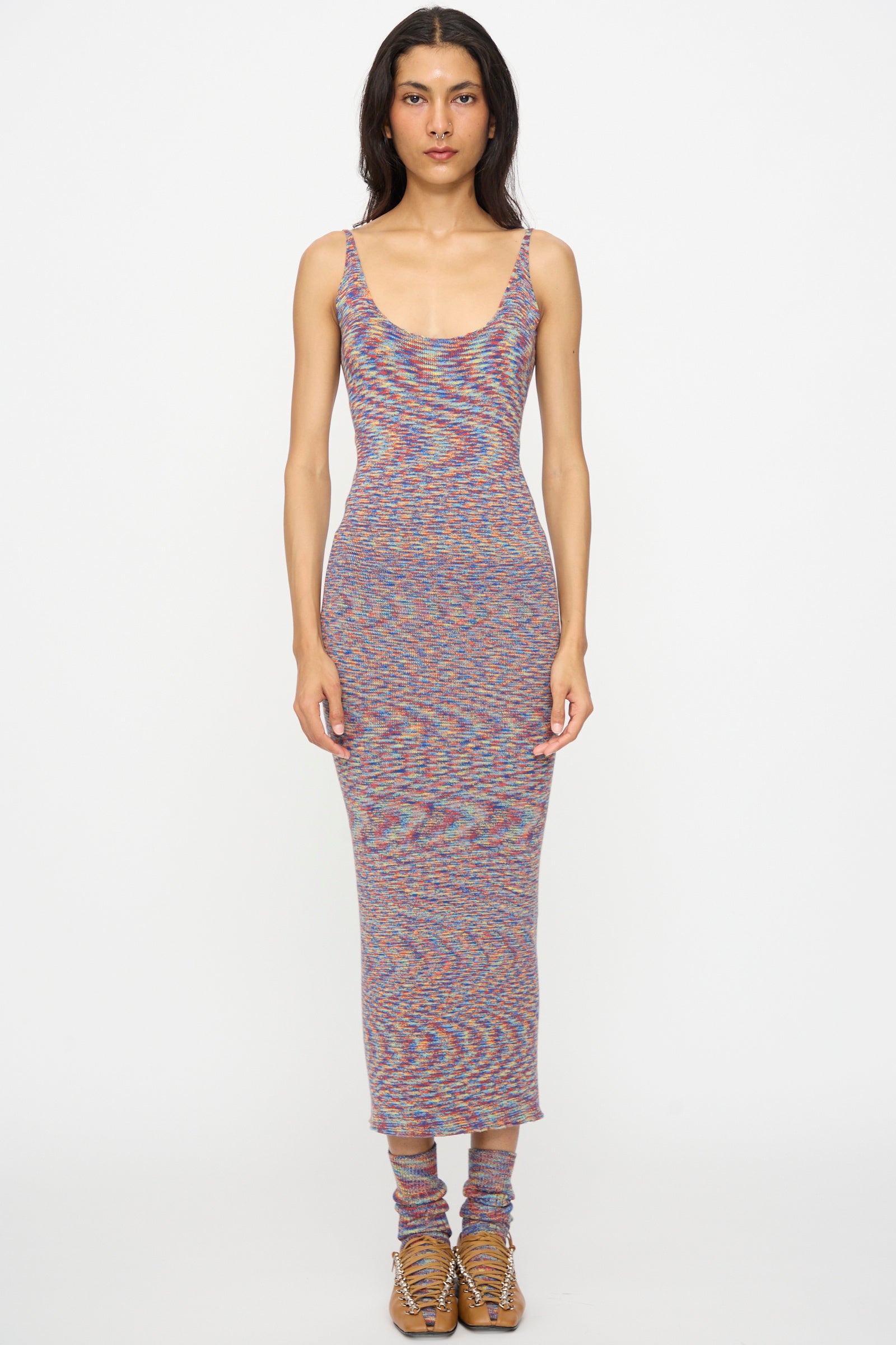 A person stands facing forward against a plain white background, wearing the Baserange Flute Dress in Multicolored, paired with matching knit socks and tan lace-up shoes.