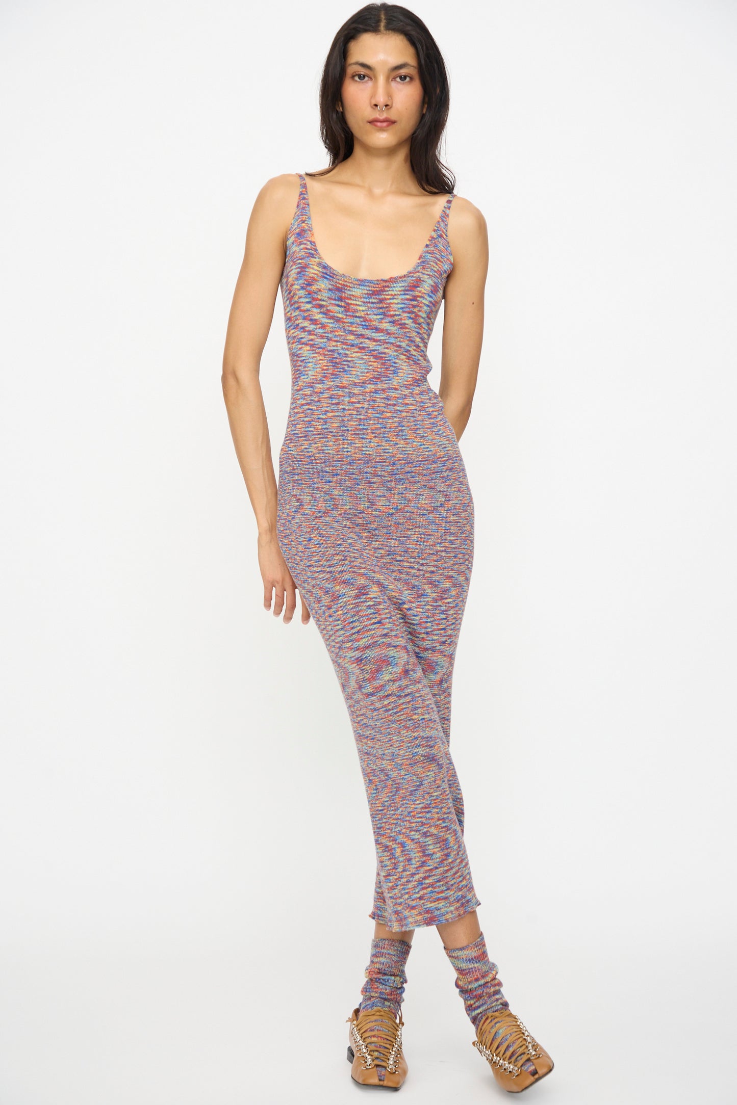 A person stands against a white background wearing the Baserange Flute Dress in Multicolored, paired with matching socks and strappy sandals.