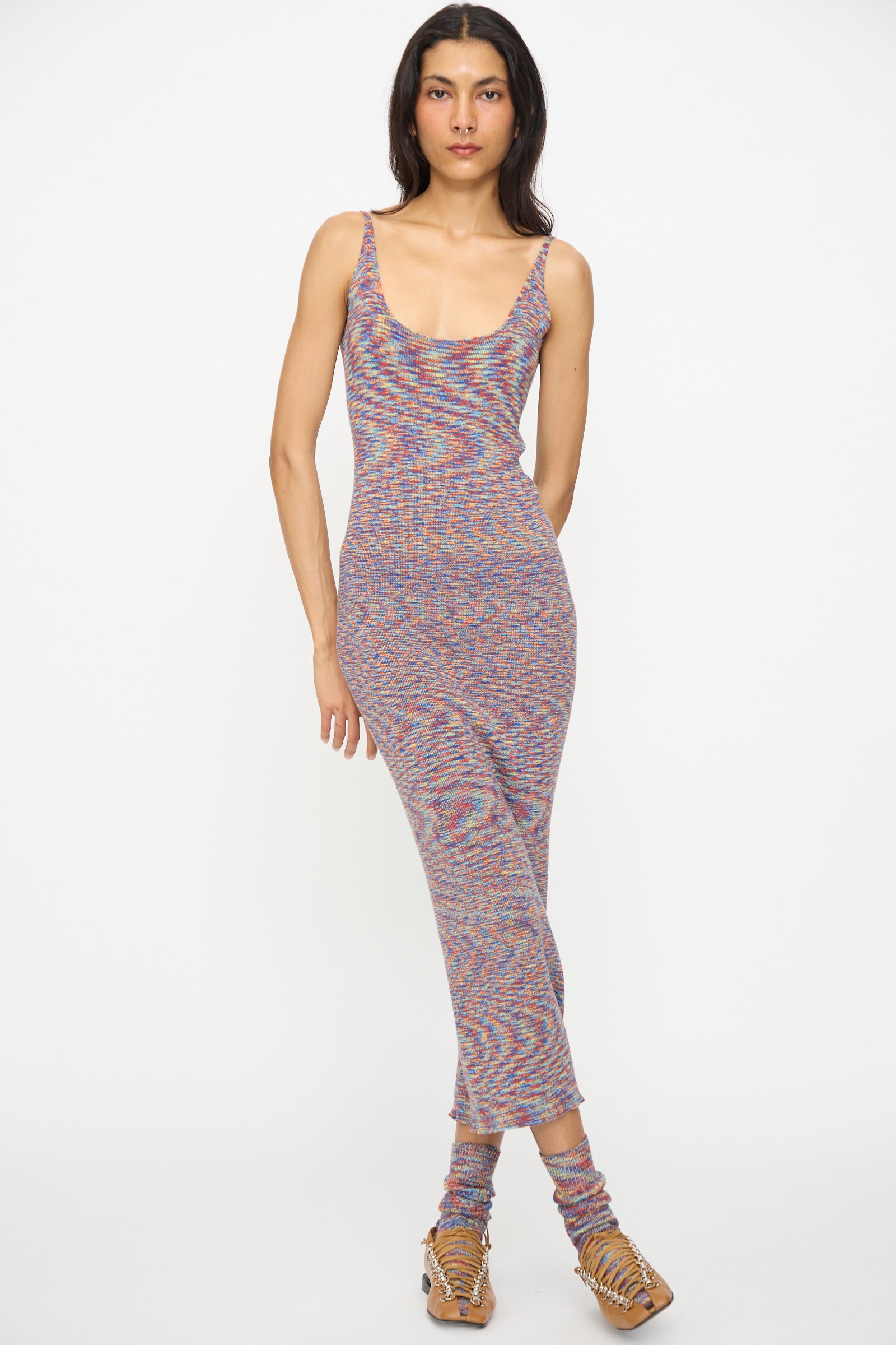 A person stands against a white background wearing the Baserange Flute Dress in Multicolored, paired with matching socks and strappy sandals.