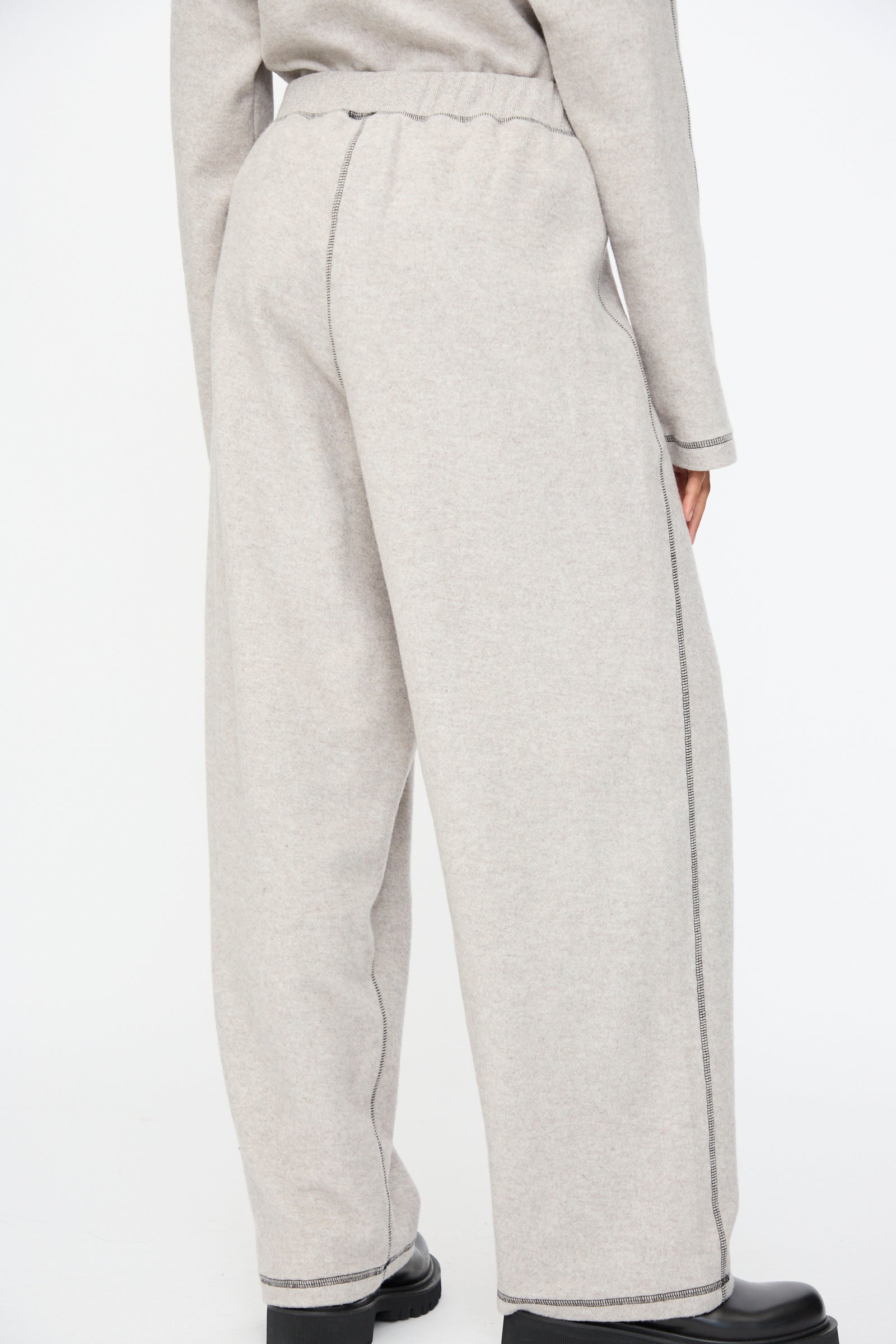 Person wearing Baserange Fold Sweatpant in Grey Melange, a relaxed-fit wide-leg style made from recycled cotton, paired with a matching top and photographed from the back against a plain white background.