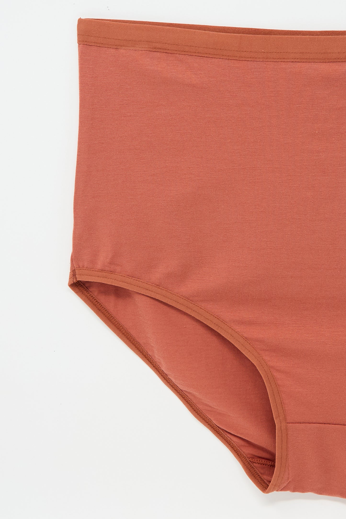 Close-up of a pair of Baserange Highwaist Bell Pants in Burned Red, featuring elastic trim and crafted from sustainable bamboo lyocell, on a plain white background.