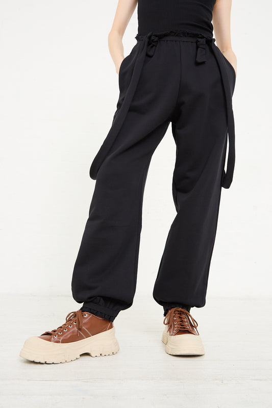Person wearing Baserange Italian Fleece Route Sweatpant in Black and chunky lace-up shoes standing against a white background.