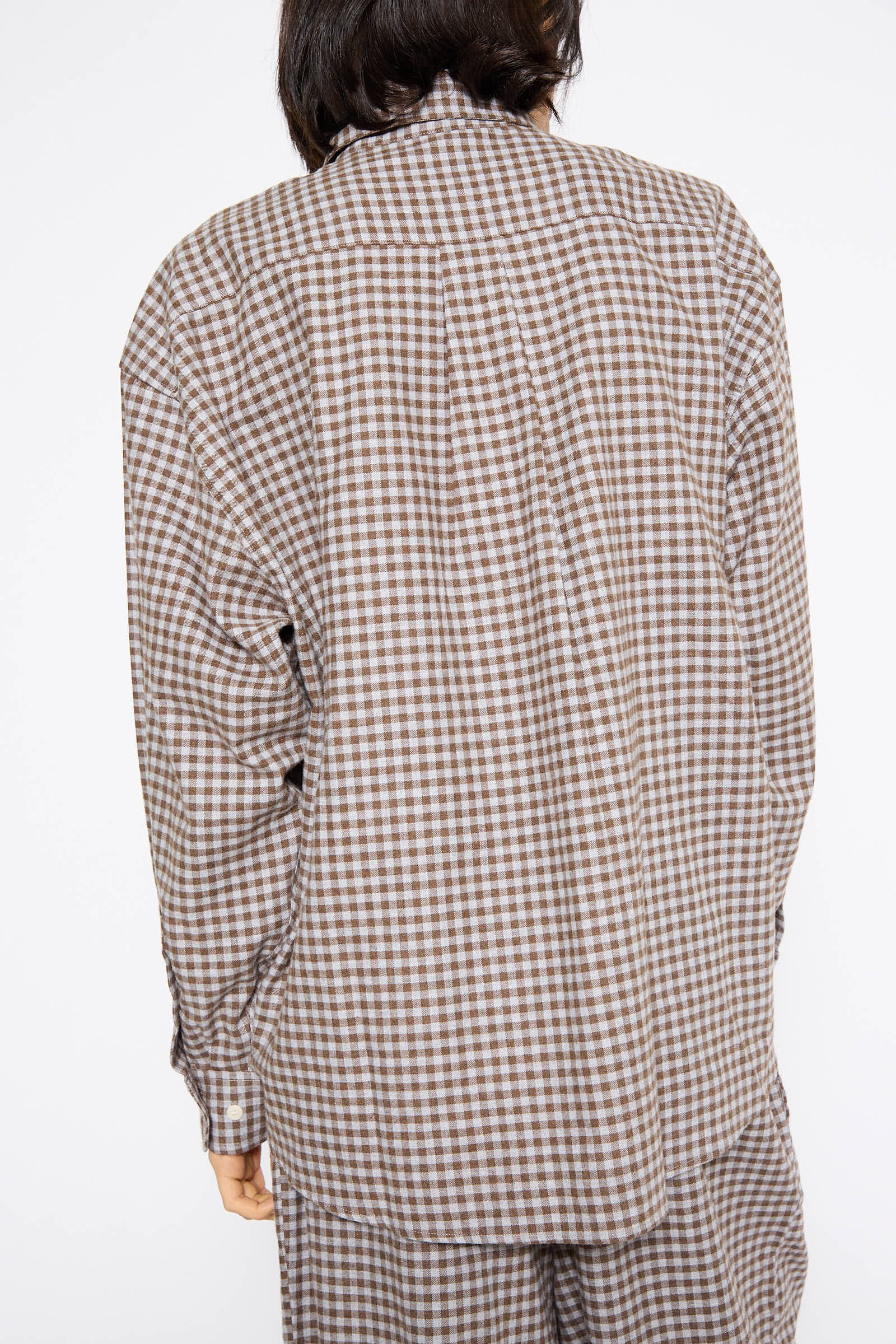 A person wearing Baserange's Loose Ole Shirt in Brown Gray Flannel, made from 100% cotton, and matching pants is shown from the back.