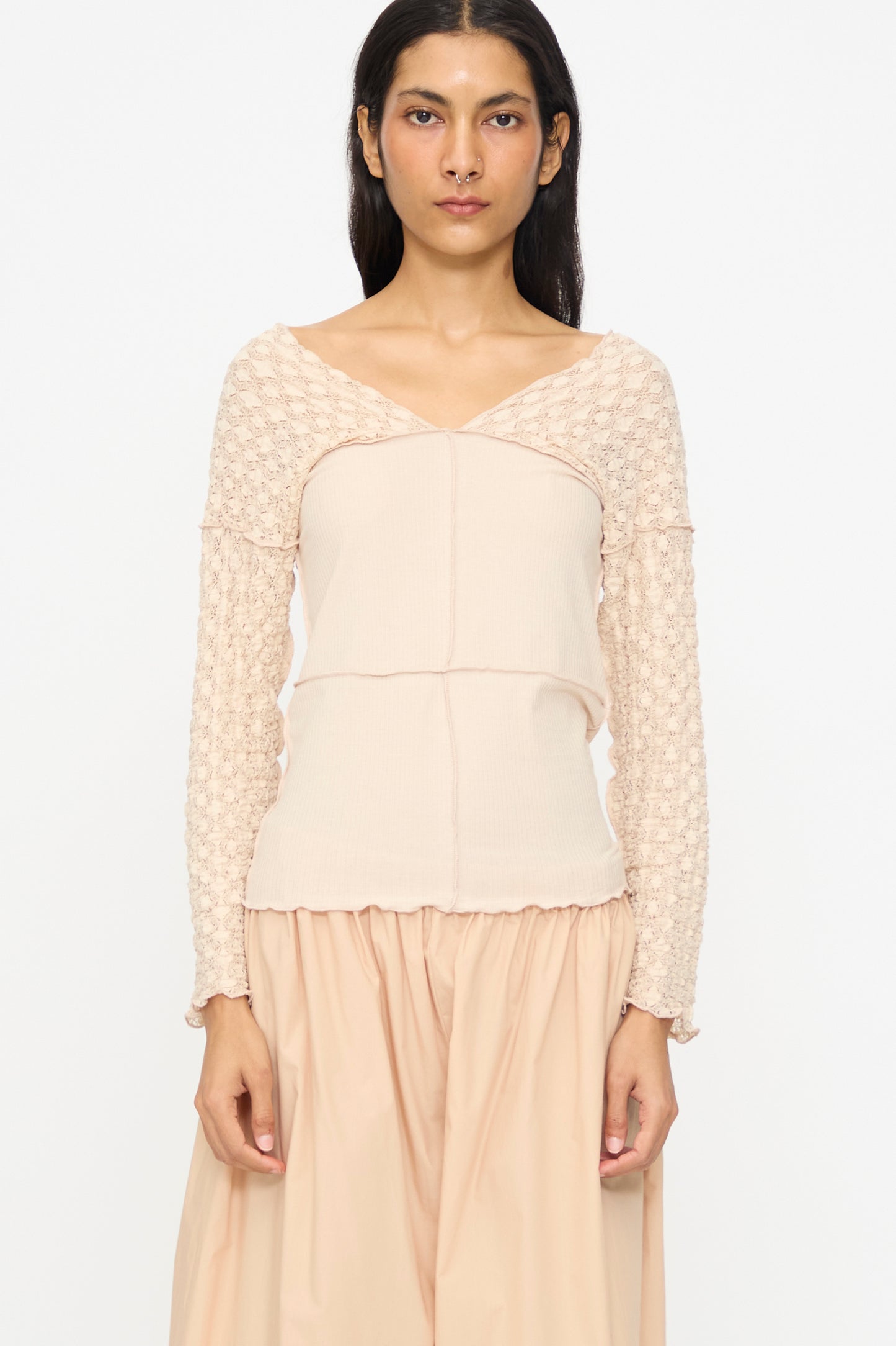 A woman wears the Baserange Nehru Long Sleeve Tee in Dylan Beige with a matching skirt, standing against a plain white background.