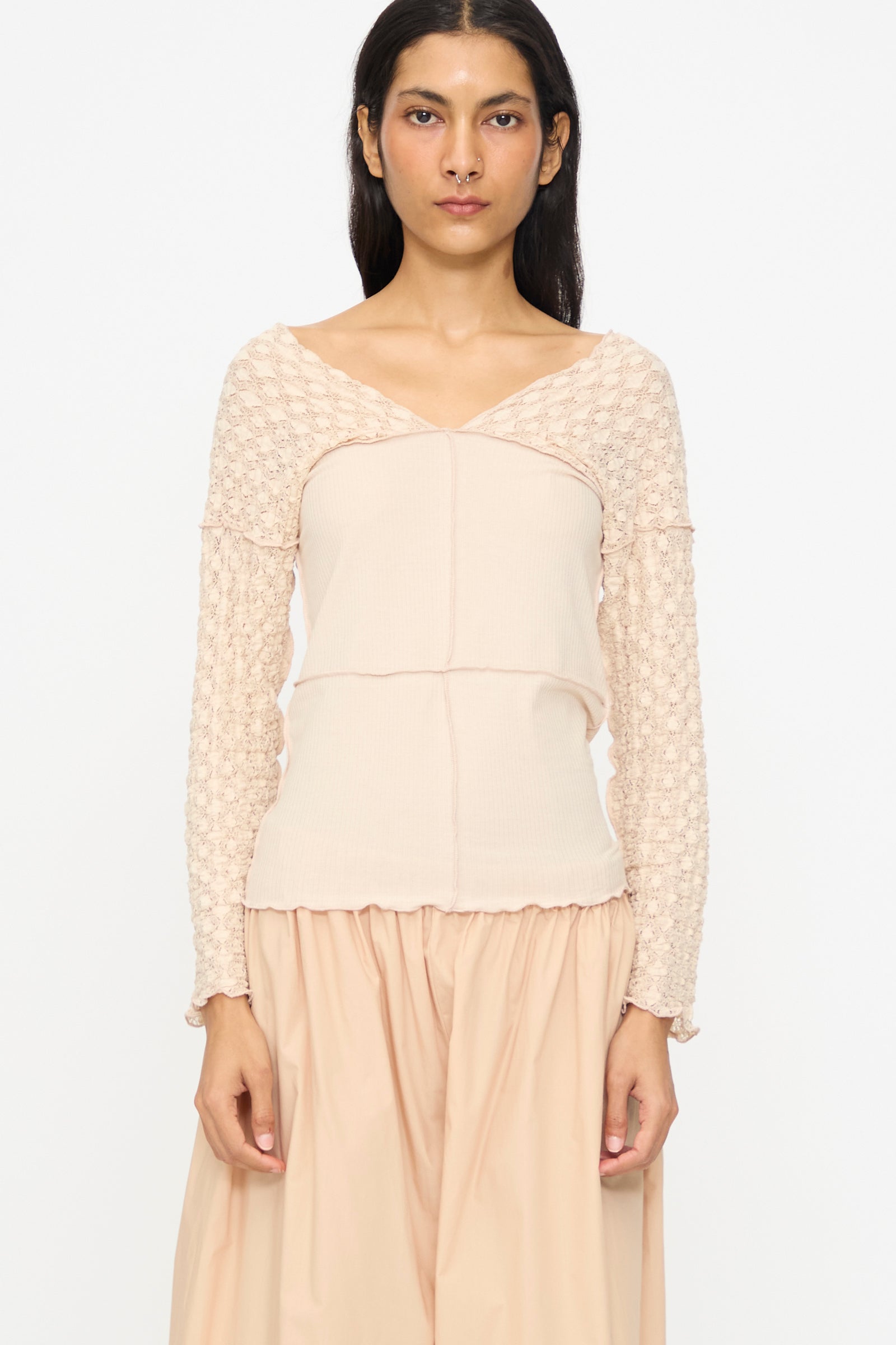 A woman wears the Baserange Nehru Long Sleeve Tee in Dylan Beige with a matching skirt, standing against a plain white background.