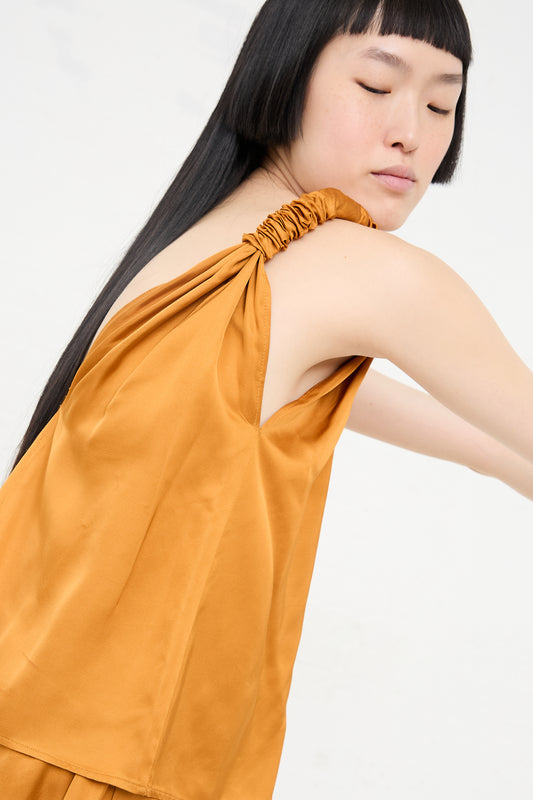 Woman in a Baserange sustainable fashion Neil Top in Mina Copper dress with a gathered shoulder detail.