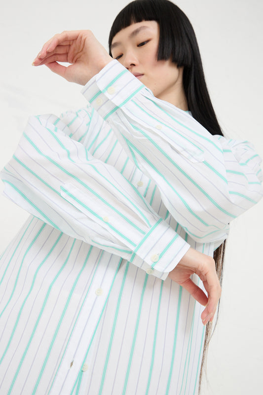 Woman with dark hair wearing a Baserange Organic Cotton Ole Shirt Dress in Stripe, striking a pose with her hand near her face.
