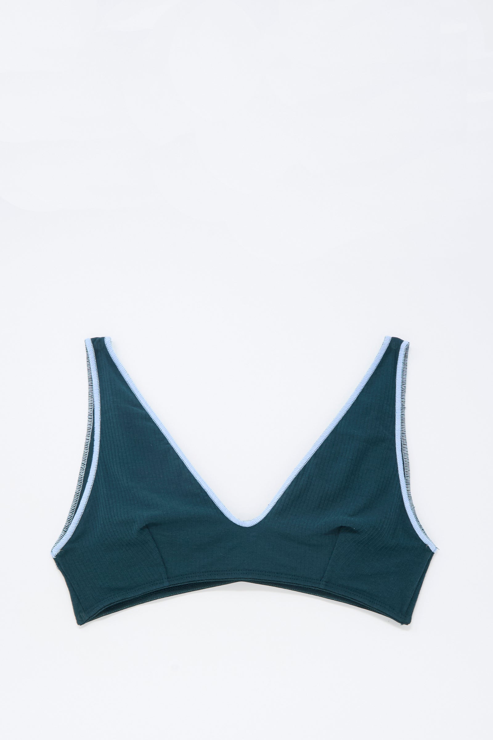 The Pam Bra in Hirsu Green by Baserange is a dark green V-neck bra made from organic cotton with light blue edging, shown flat on a white background—an elegant piece for women's lingerie collections.