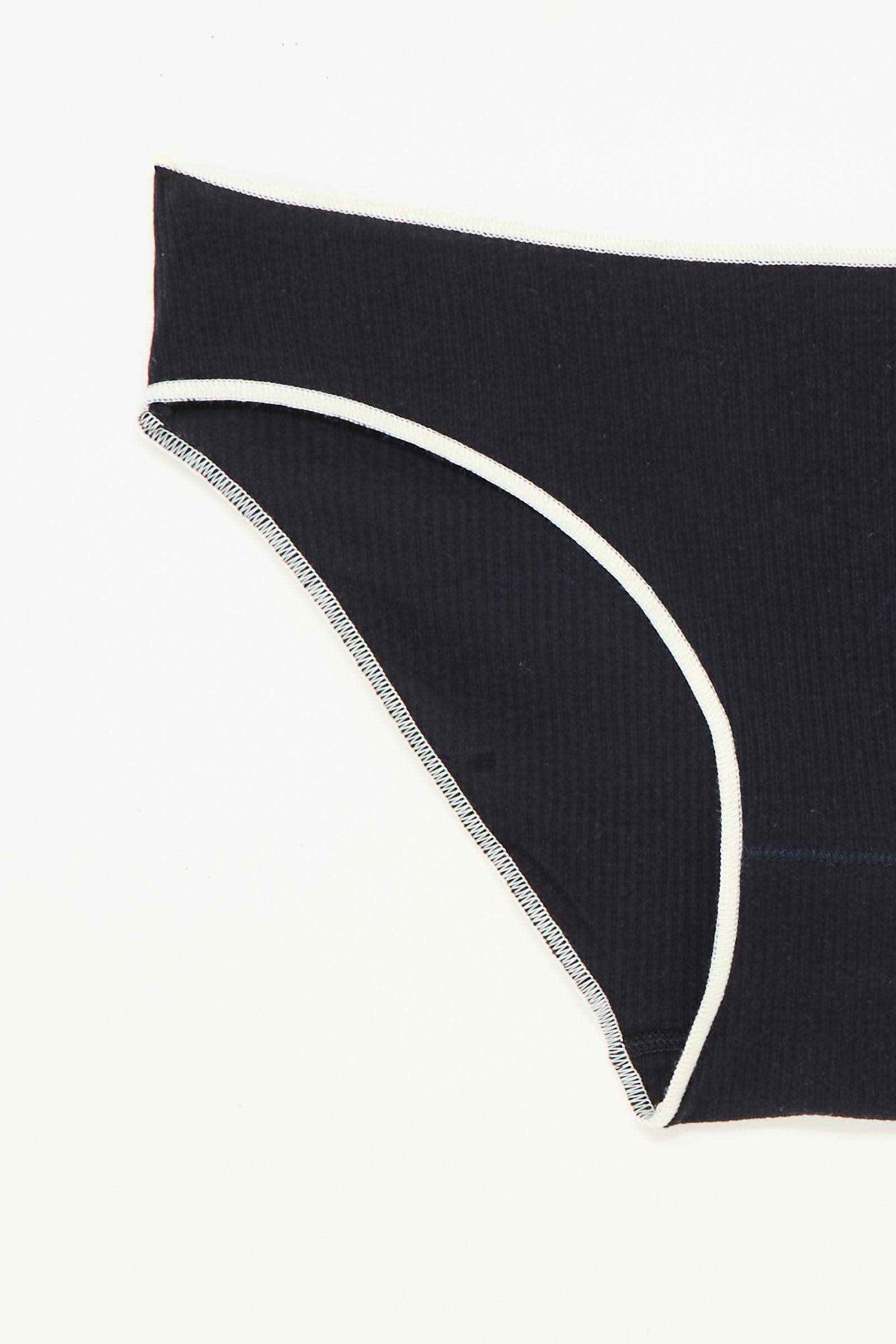 A close-up of the Baserange Pam Pant in Murano Navy, a ribbed organic cotton brief with white trim, laid flat on a white background.