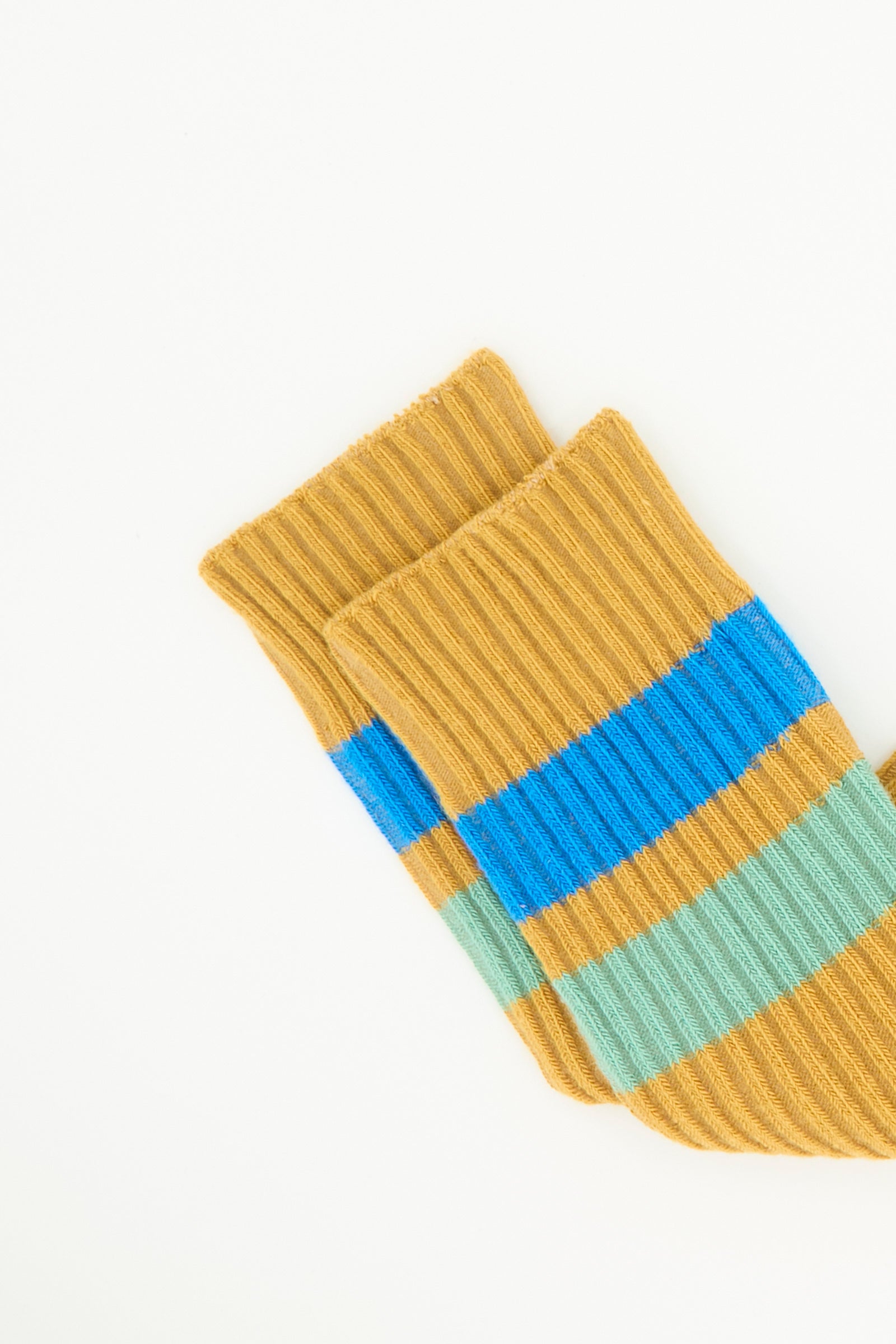 A pair of Baserange Race Knee Socks in Silva Brown, crafted from cotton rib and featuring mustard yellow, blue, and light green horizontal stripes. Made in France and displayed on a white background.