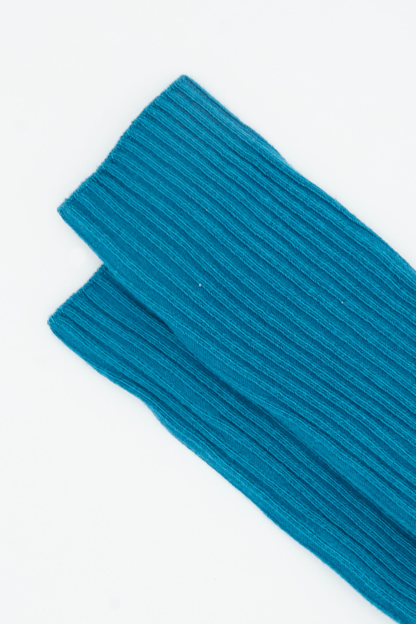 Close-up of two folded Sphere Blue Rib Knee Socks by Baserange, featuring a cotton blend knit reminiscent of over-knee socks, laid on a white background.