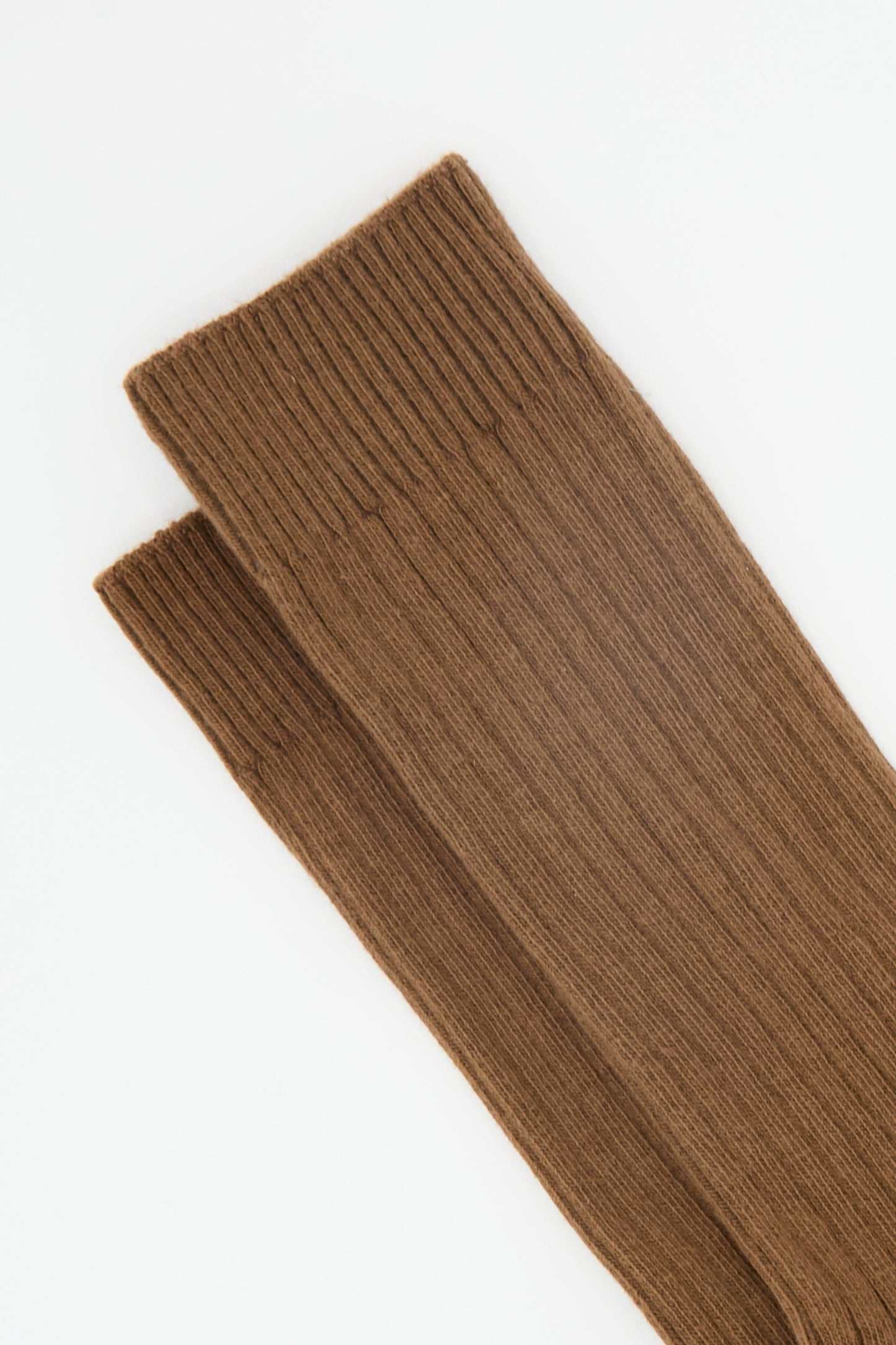 A pair of Baserange Rib Overankle Socks in Nocciola Brown, crafted from organic cotton, is laid flat on a white background.