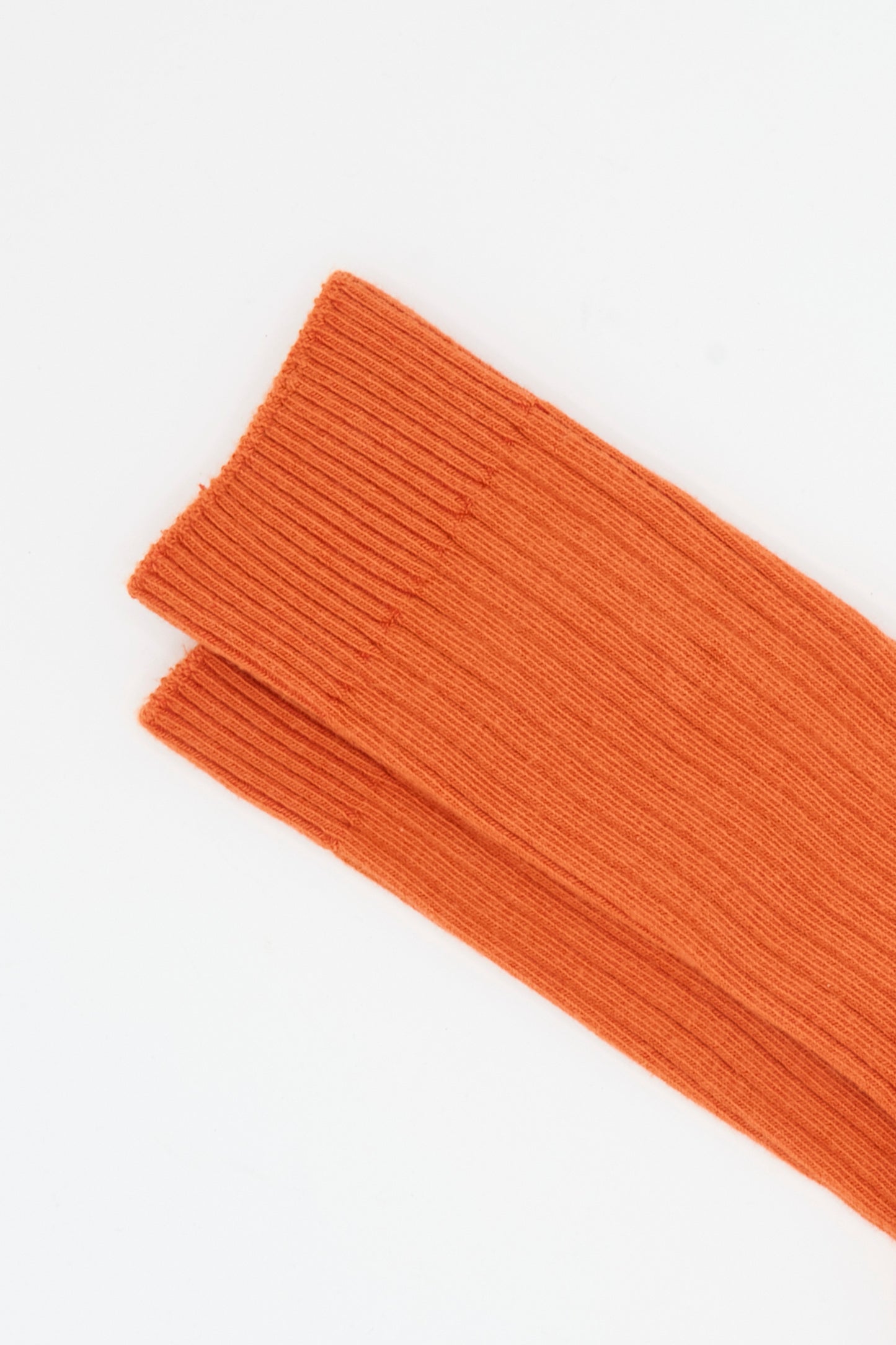 Two ribbed knit sleeves in Scopa Red from Baserange are laid side by side on a white background, echoing the texture of the Rib Overankle Socks made in France.