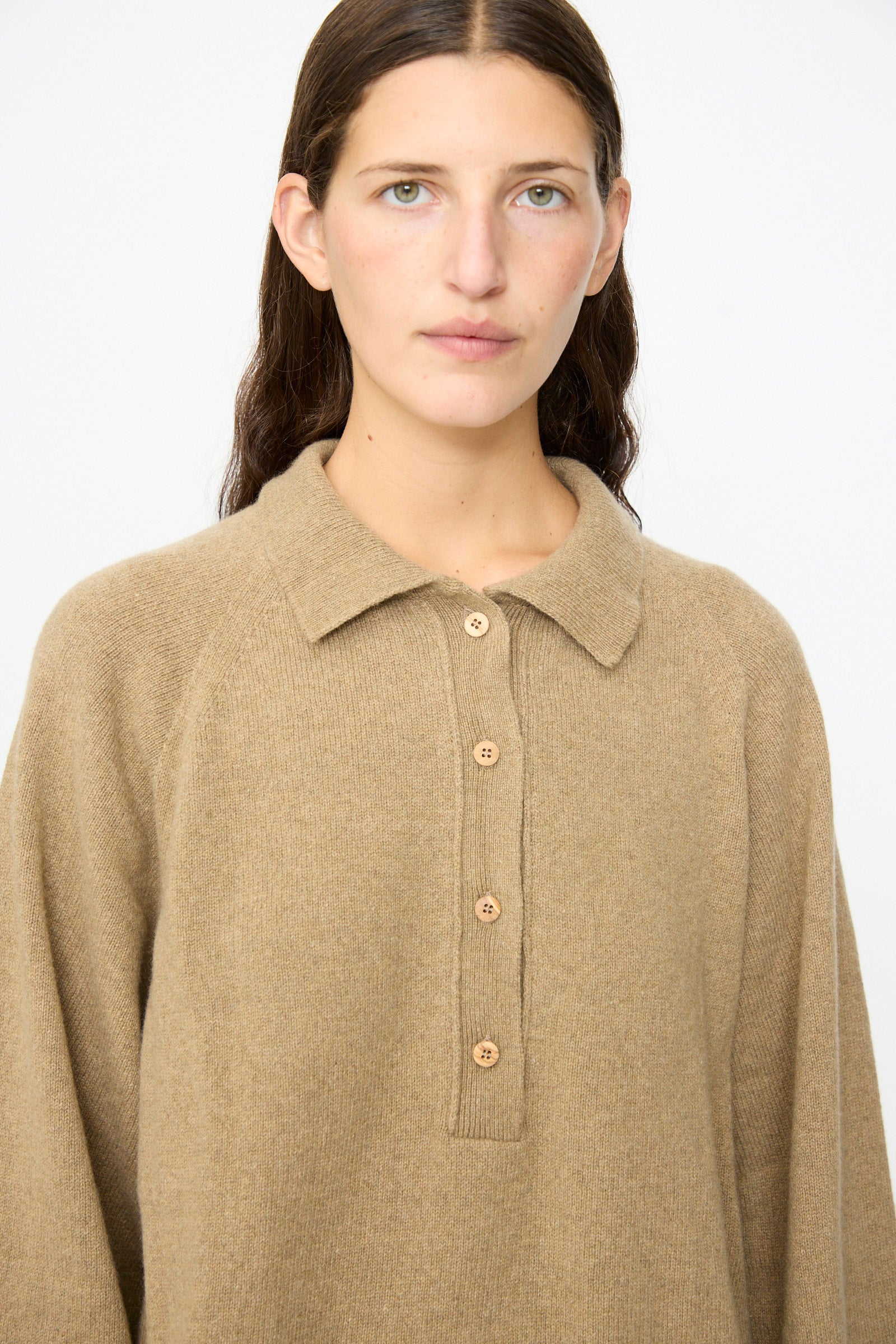 A person with long brown hair wearing the Baserange Soar Polo in Rovere Brown stands against a plain white background.