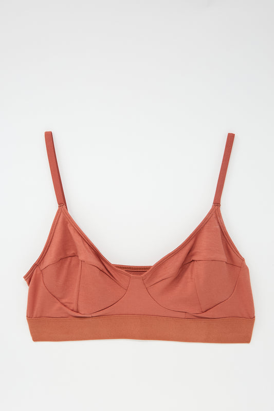 A Baserange Soft Bra in Burned Red, featuring adjustable straps and a seamless bamboo jersey design, is laid flat on a white background.