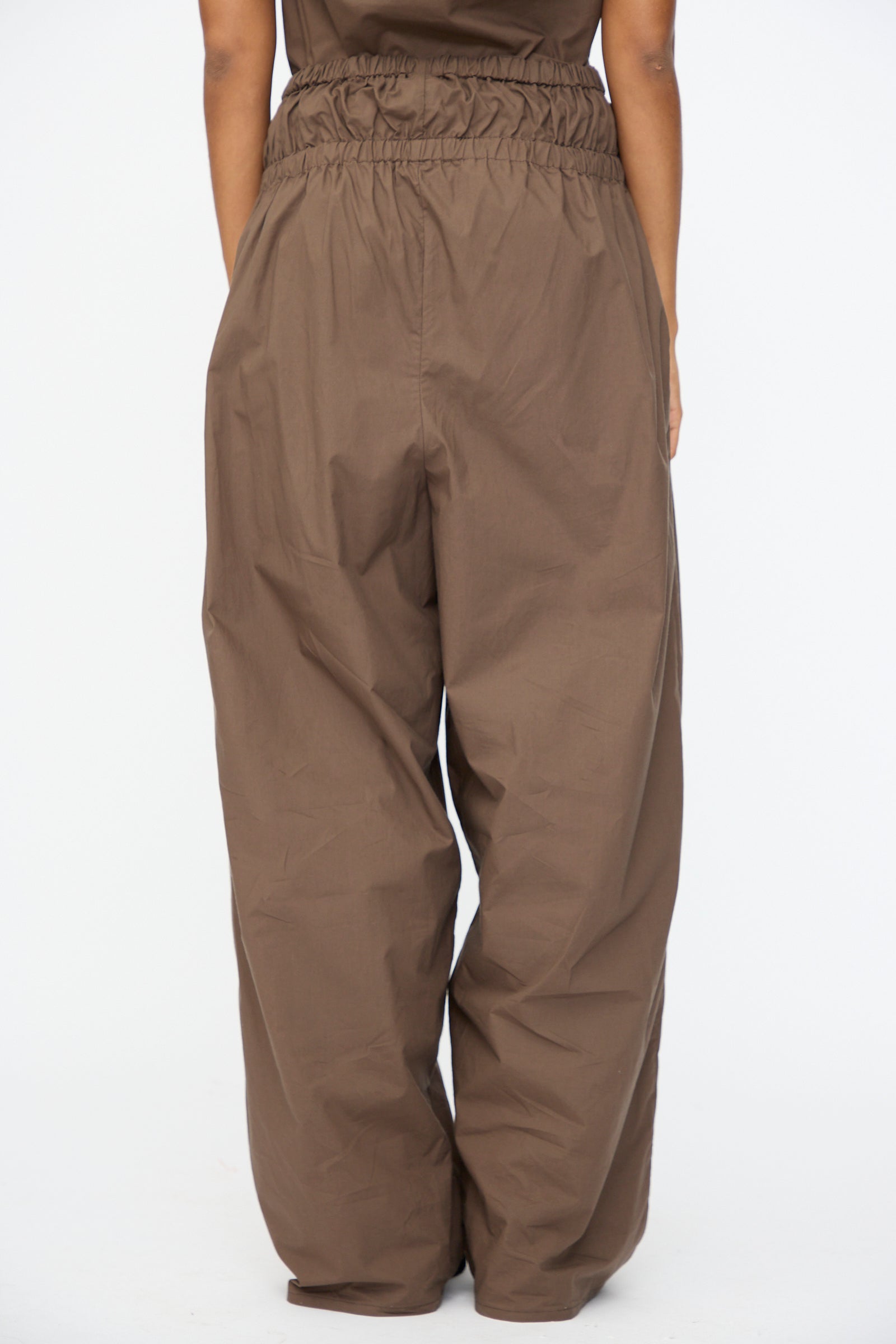 Person wearing the Baserange Tin Pant in Mara Brown, shown from the back against a plain white background.