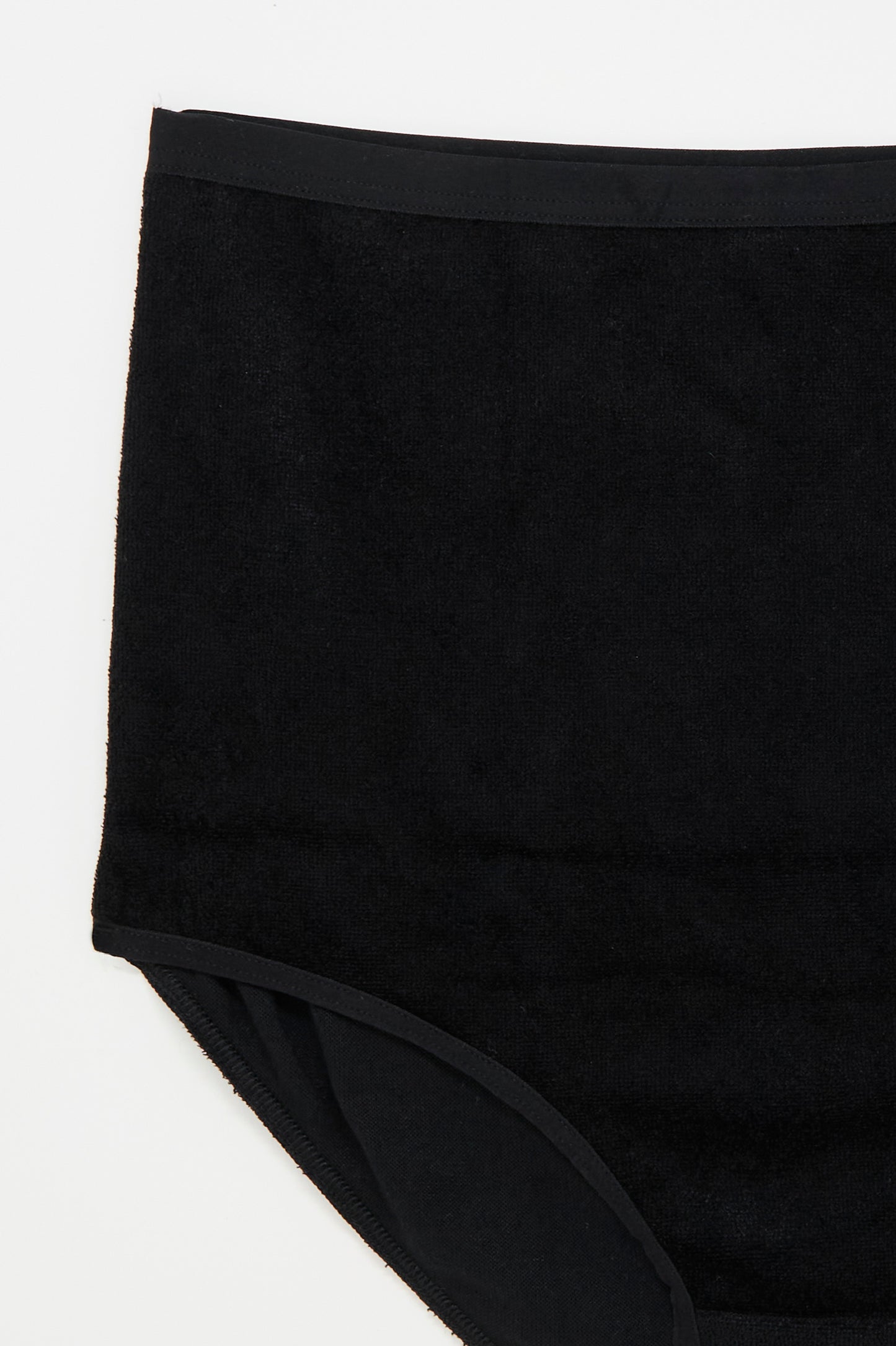 Close-up of the Velour Highwaist Bell Pant in Black by Baserange on a white background, showcasing the smooth fabric texture and simple design.