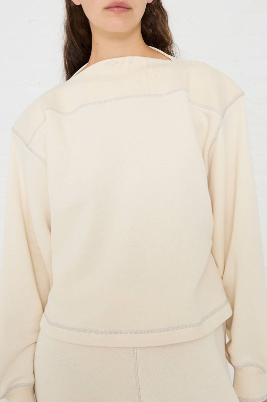 A person wearing a long-sleeved off-white Way Boat Sweatshirt in Undyed Path Grey by Baserange and matching pants stands against a plain white background. Only the lower part of their face and upper torso are visible.