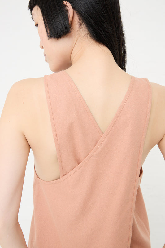 A woman with short hair wearing a sleeveless Wild Silk Apron Top in Sid Pink by Baserange with a v-back design, embodying sustainable fashion.
