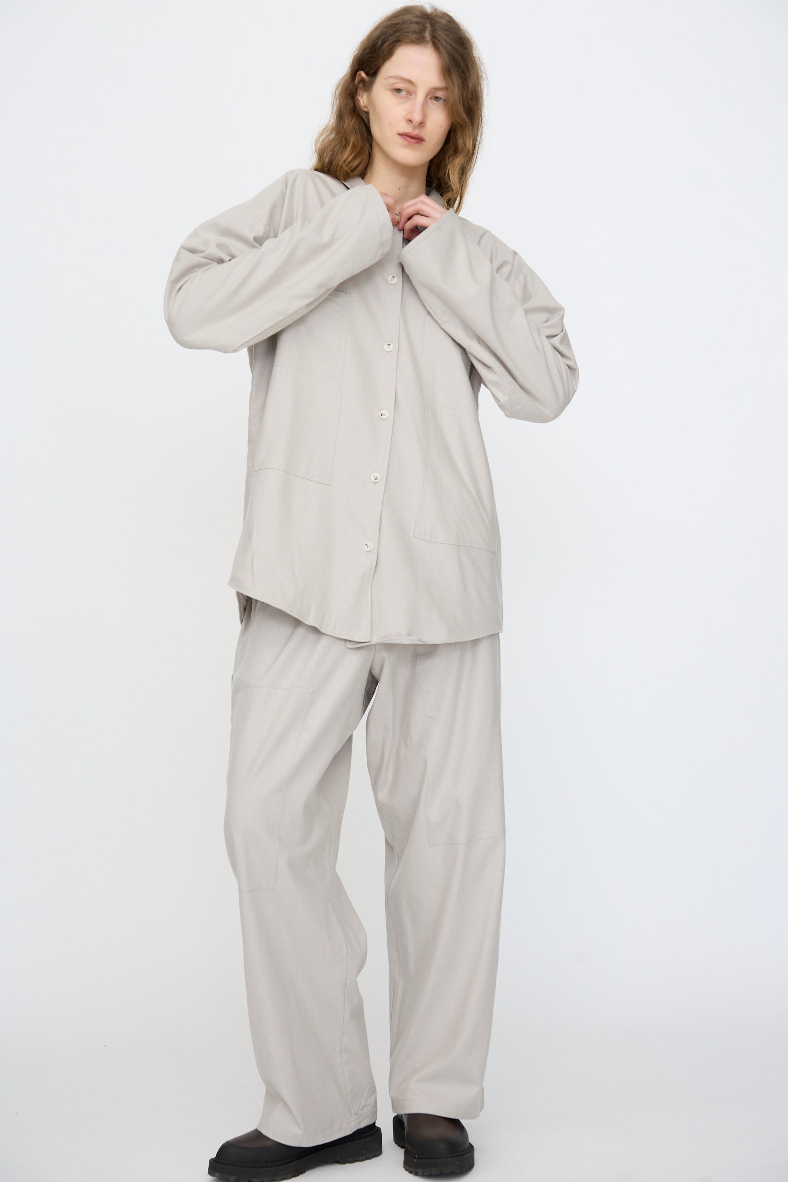 A person wears the Baserange Wild Silk Gren Overshirt in Prun Grey, crafted in Türkiye, paired with matching wide-leg pants, standing against a plain white background.