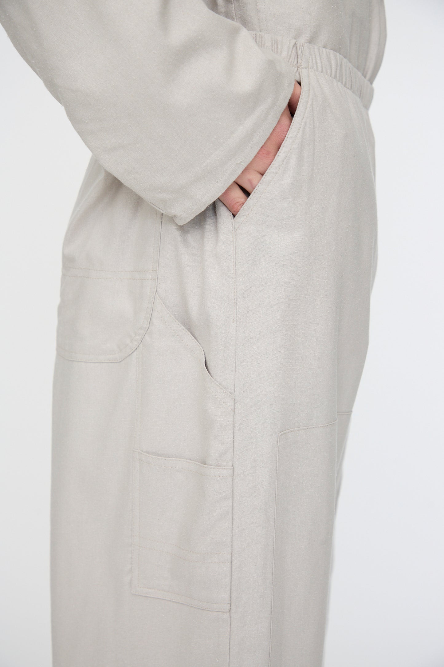 A person is shown from the side wearing Baserange's Wild Silk Gren Pant in Prun Grey, featuring a relaxed fit, elasticated waistband, and multiple pockets, with one hand tucked into a pocket.