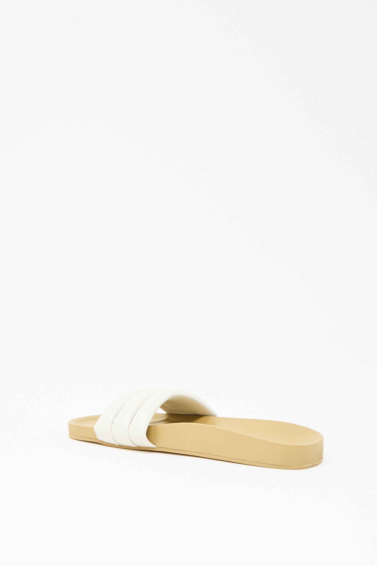 The Classic Sandalia in Shell by Beatrice Valenzuela is a handcrafted beige leather slide sandal featuring a wide white strap, shown against a plain white background.