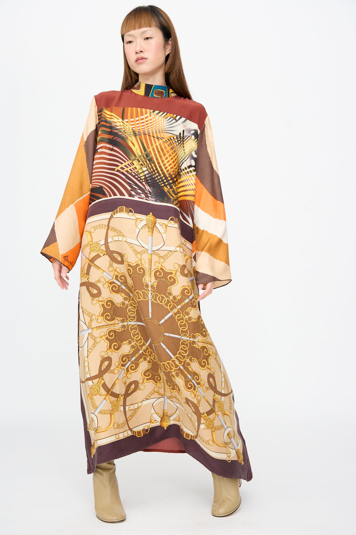 A person wears a Bettina Bakdal Classic Mandarin Collar Dress in Benita Otte, a vintage silk, long-sleeve maxi dress featuring a brown and gold chain-link pattern and a mandarin collar.